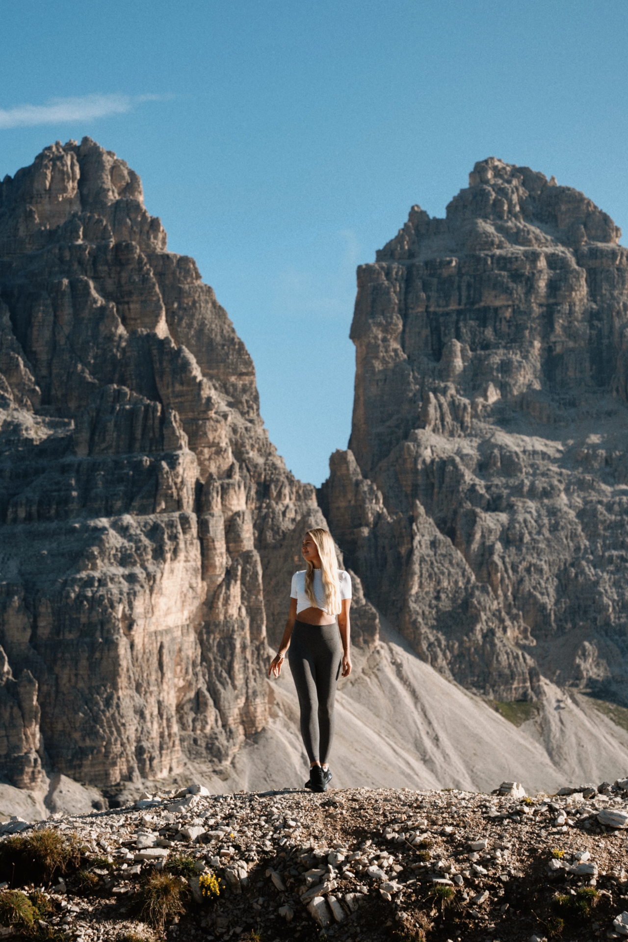 Woman standing on rocky terrain in front of dramatic Dolomites peaks at Cadini di Misurina.