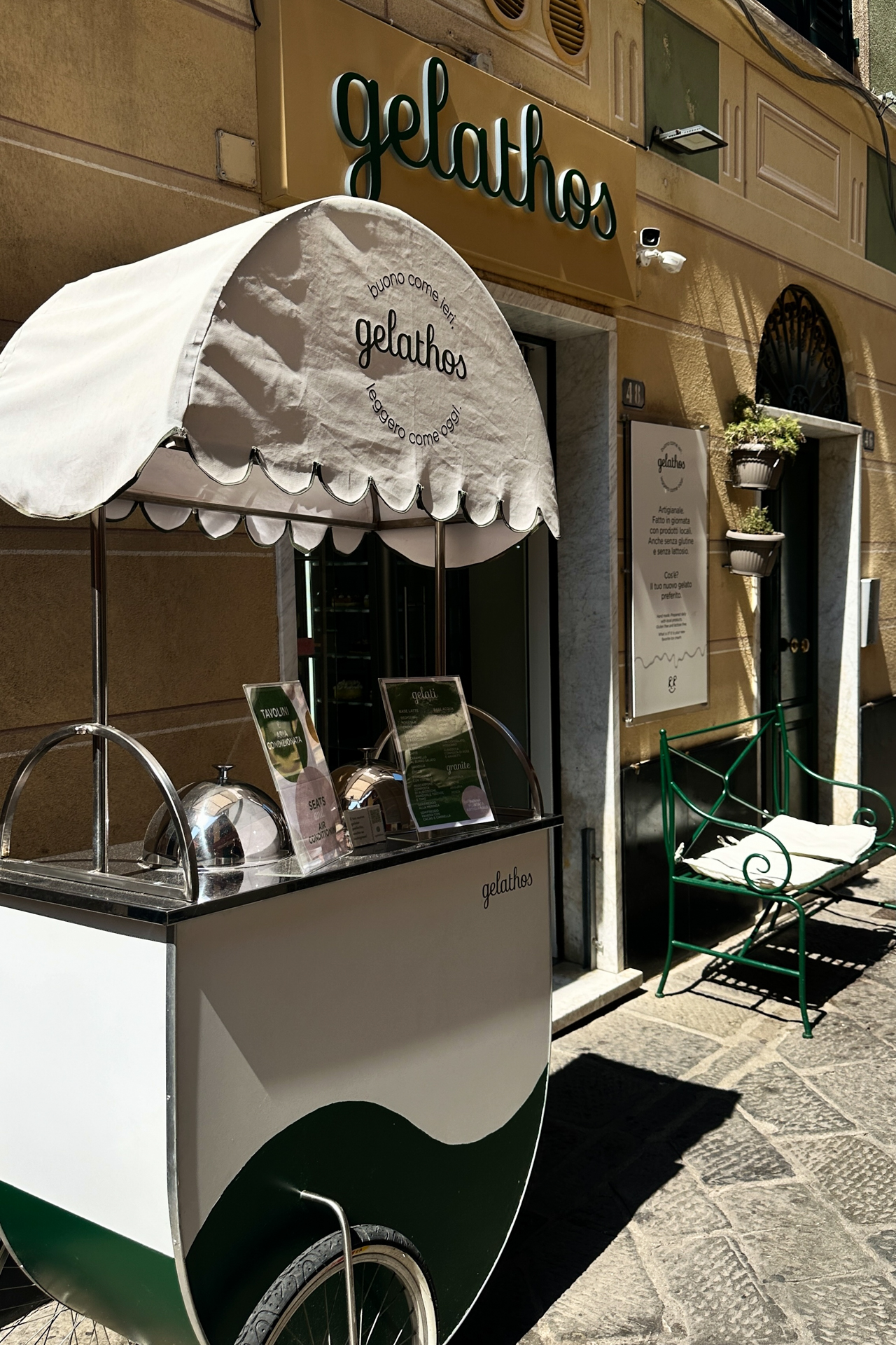 A charming gelato cart outside Gelathos in Sestri Levante old town under warm sunlight.