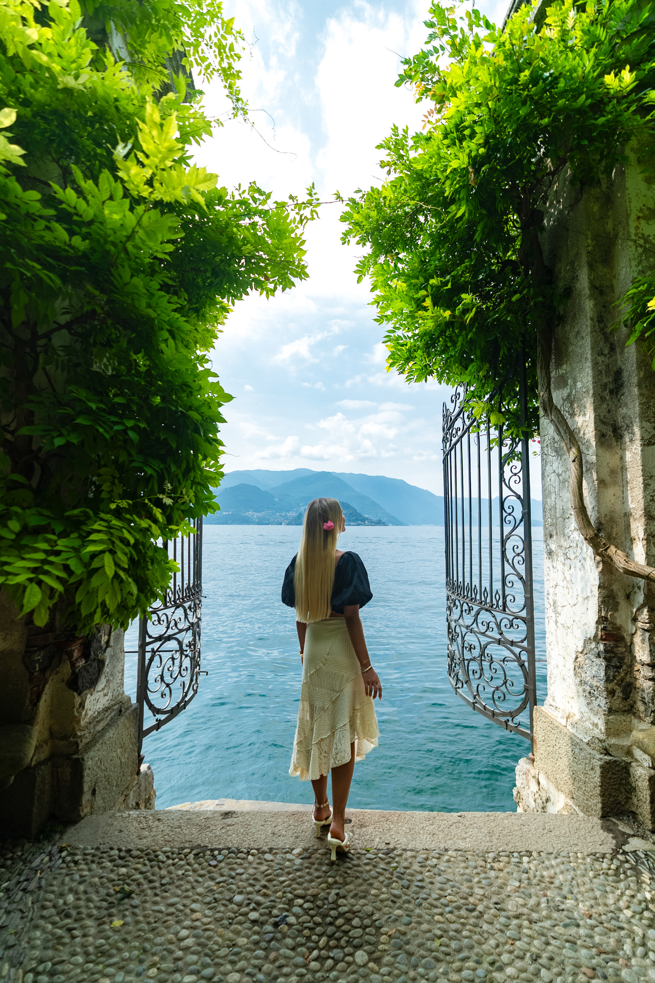 Woman overlooking Lake Como in Varenna and mountains at Villa Cipressi, Italy.