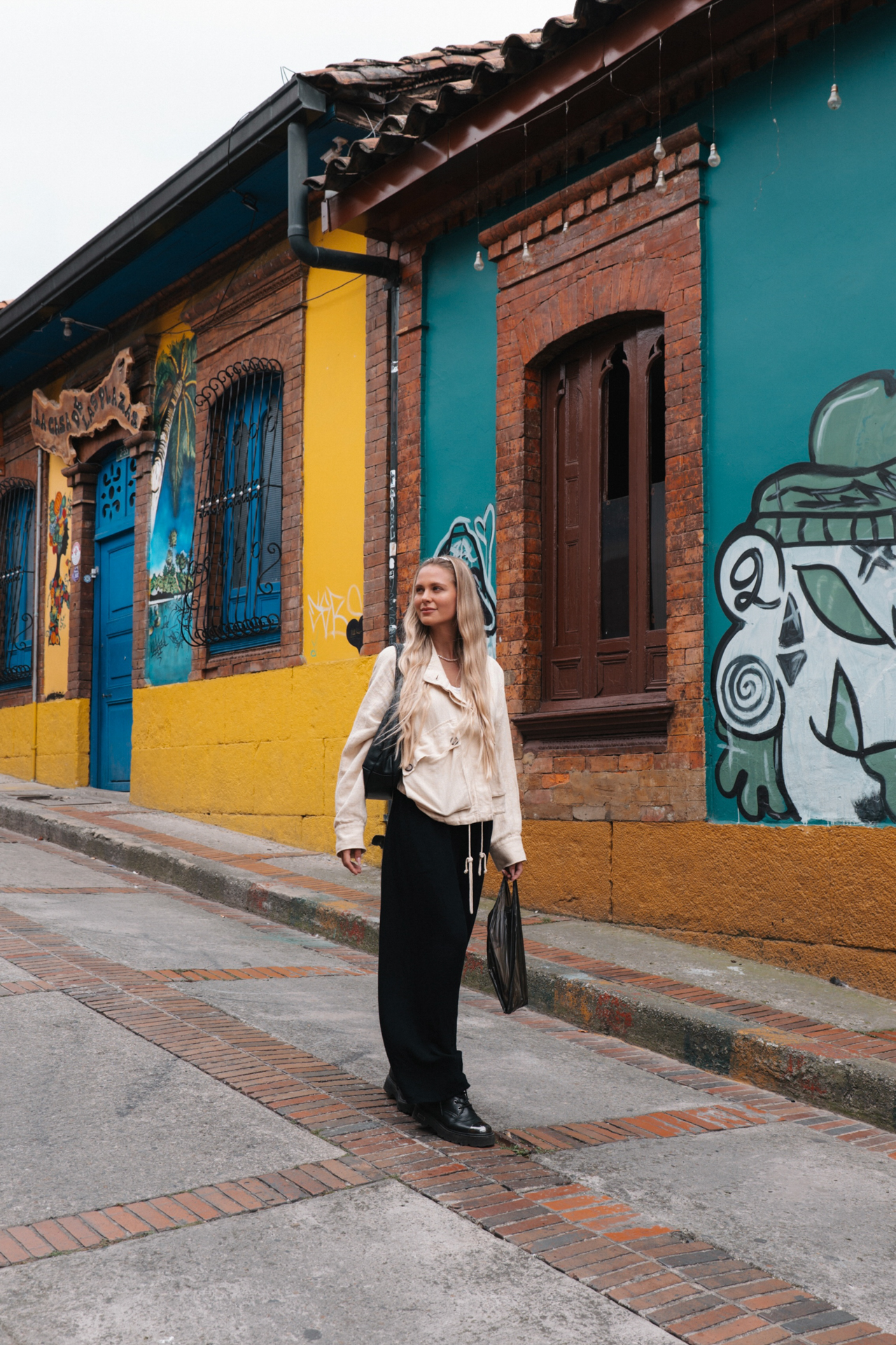 Woman exploring the colorful streets of La Candelaria in Bogotá, Colombia, with vibrant murals and colonial architecture.