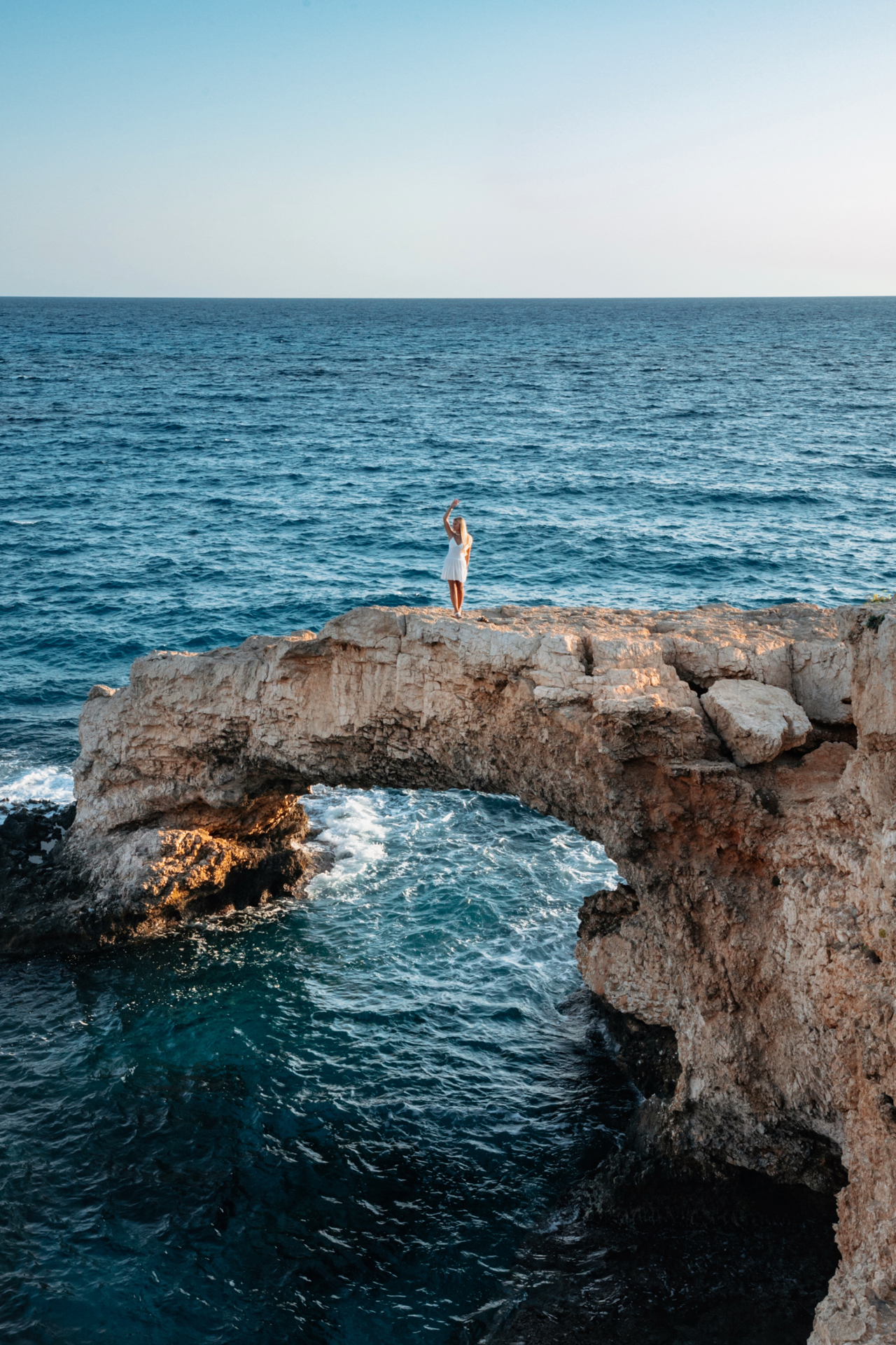 Woman standing on the natural rock arch “Bridge of Lovers” above the sea in Ayia Napa.