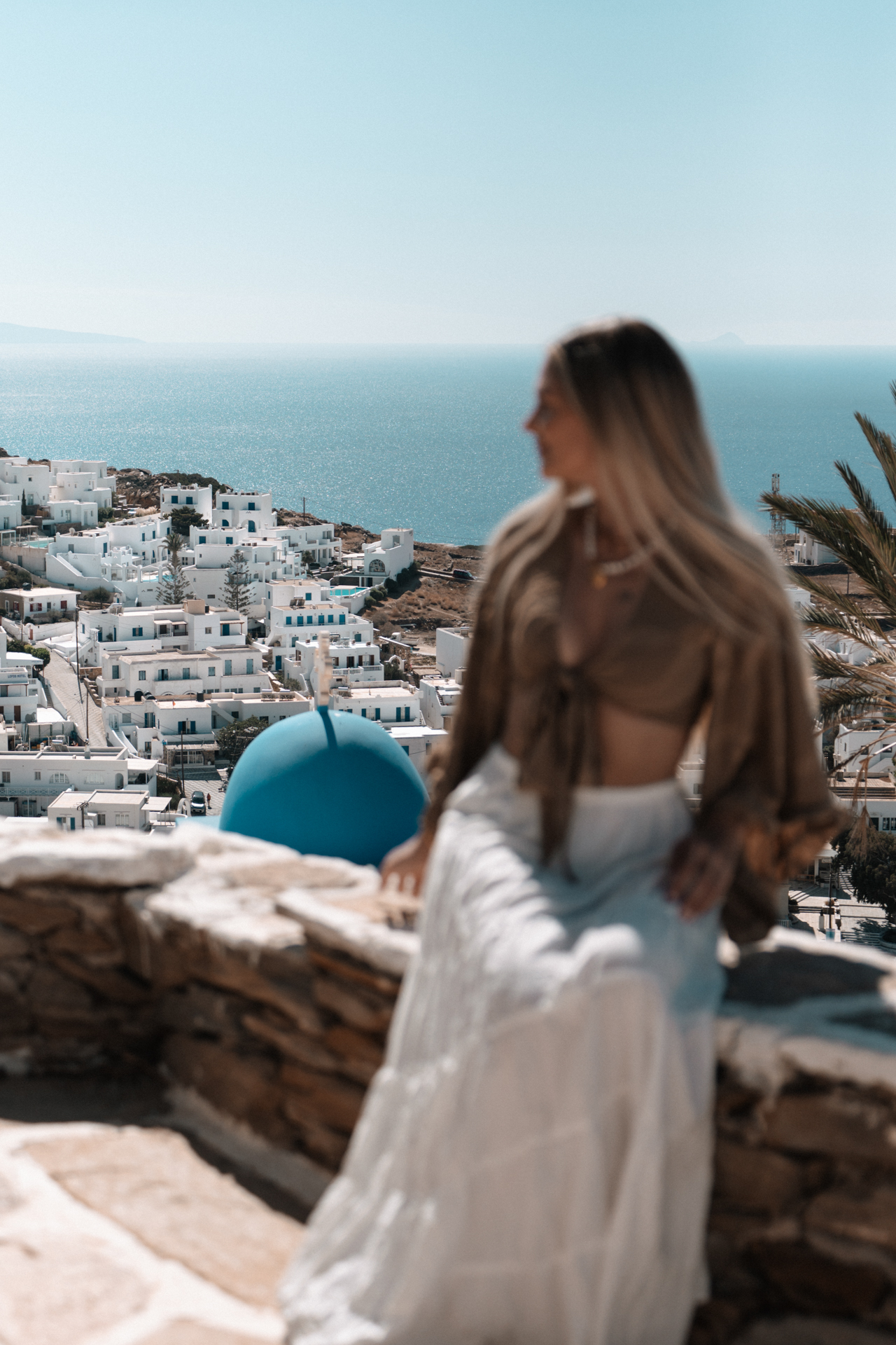 Ios Woman overlooking white Cycladic houses and blue sea in Ios, Greece.