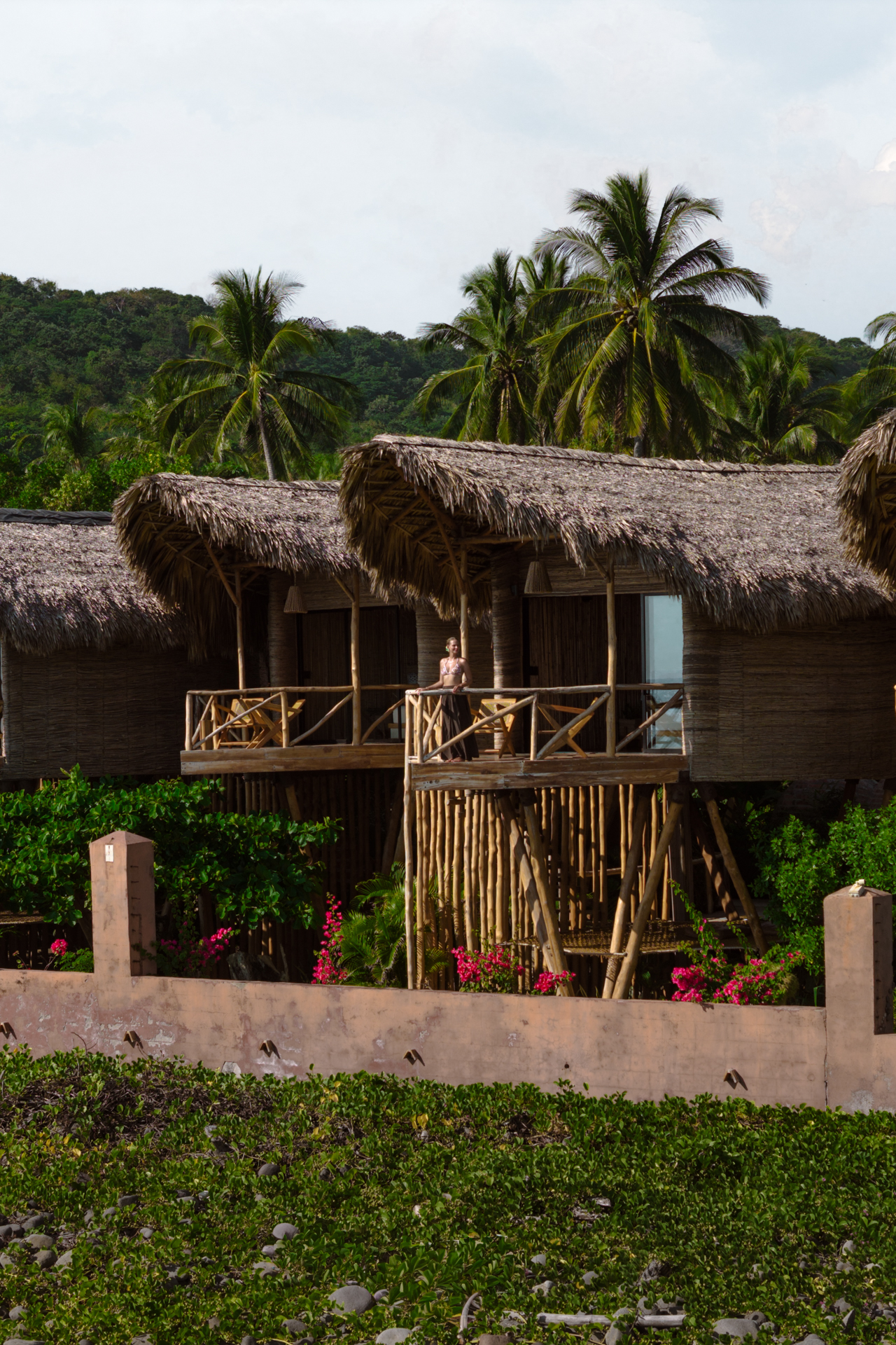 Mizata Traveler standing on the balcony of Nawi in a a bamboo bungalow at Mizata, El Salvador.