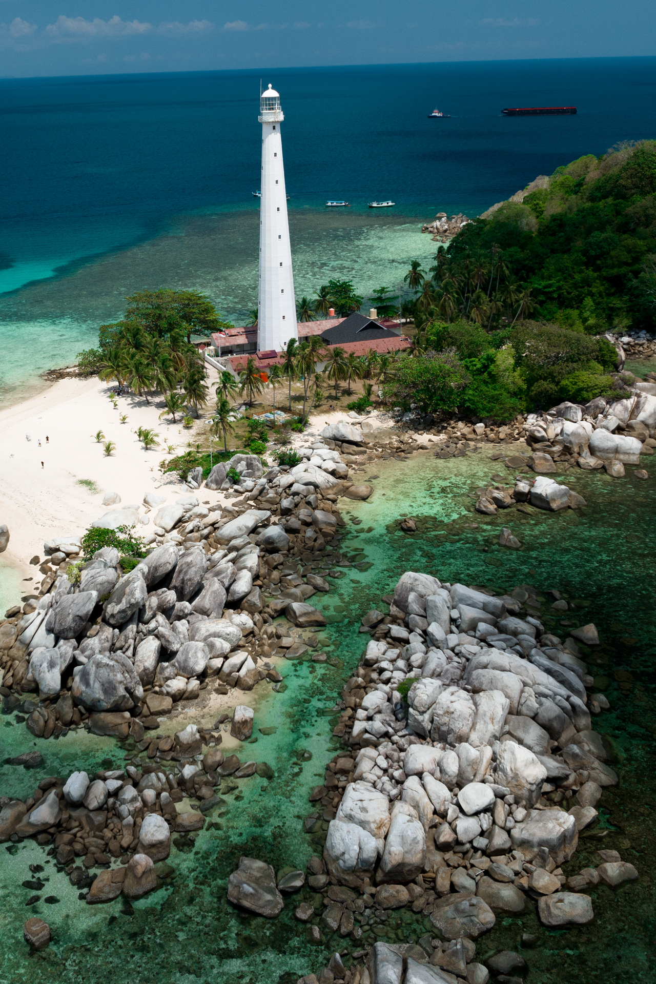 Lengkuas Island lighthouse surrounded by granite rocks and clear turquoise sea in Belitung
