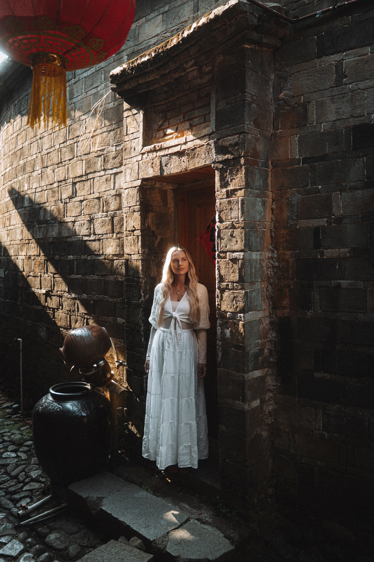 China Woman in white dress at traditional Fujian stone building, China