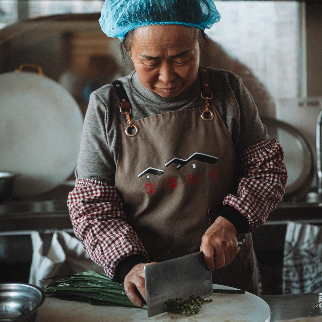 Food in China : Local Chinese woman chopping fresh herbs on a wooden cutting board in a traditional kitchen in Fujian, China