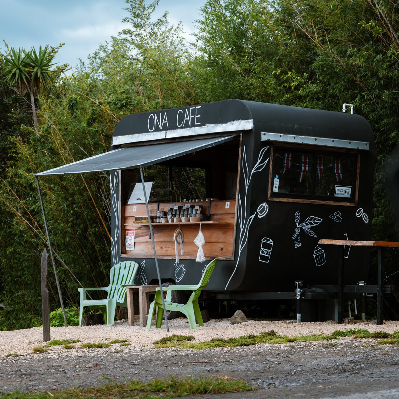 Minimalist black Ona Cafe coffee trailer surrounded by lush greenery in Costa Rica
