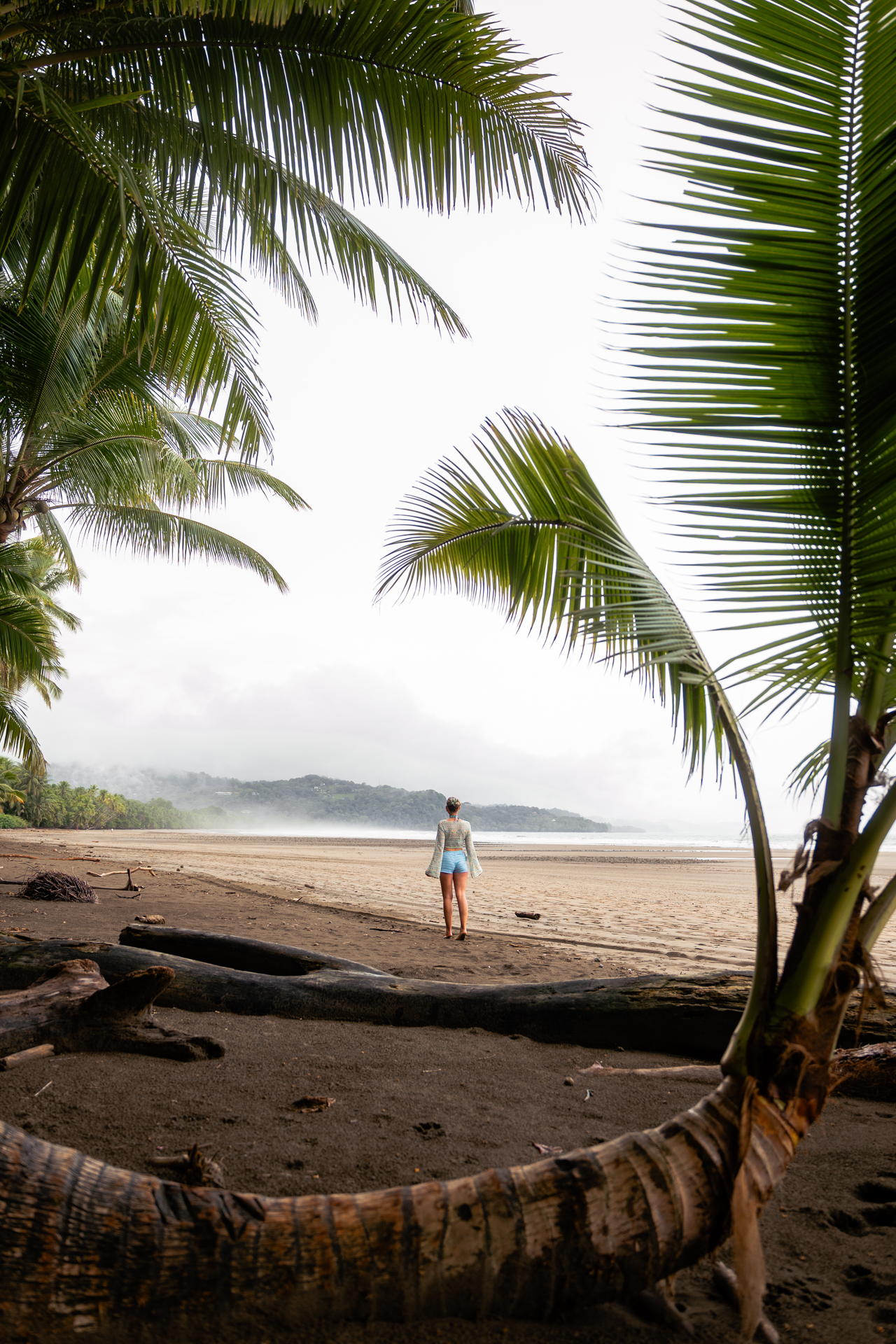 Person standing on a quiet black sand beach in Uvita, Costa Rica