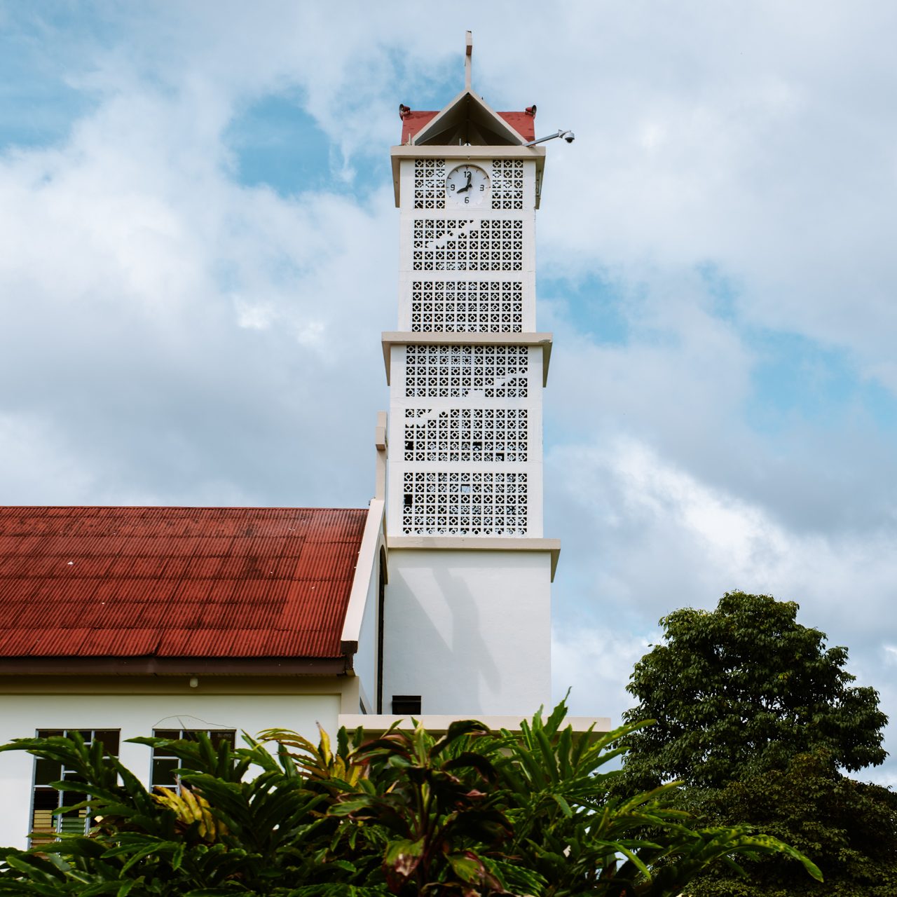 Church tower with red roof and tropical greenery in Costa Rica