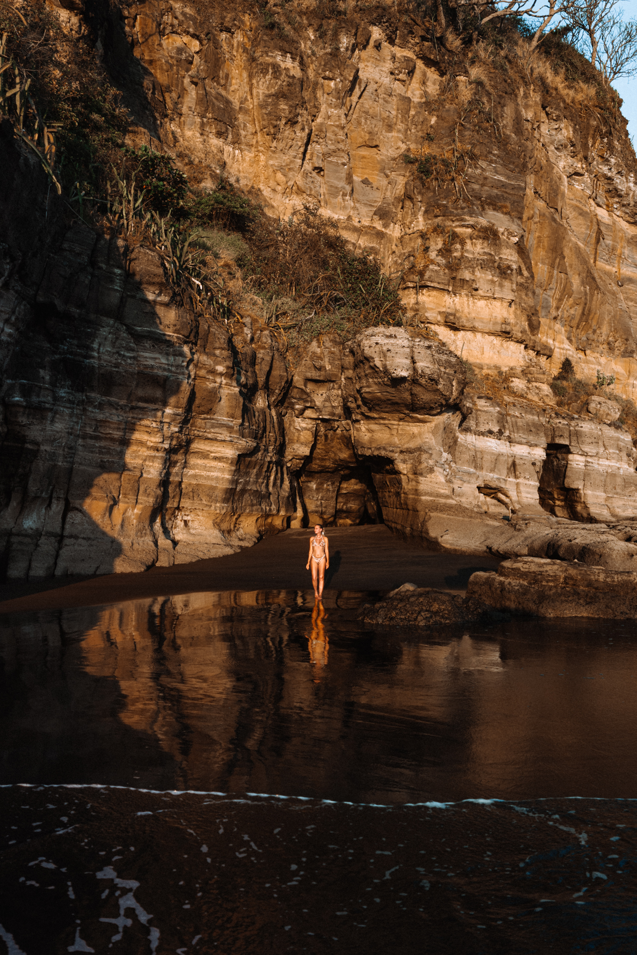 Woman standing by rock formations at sunset, El Zonte, El Salvador