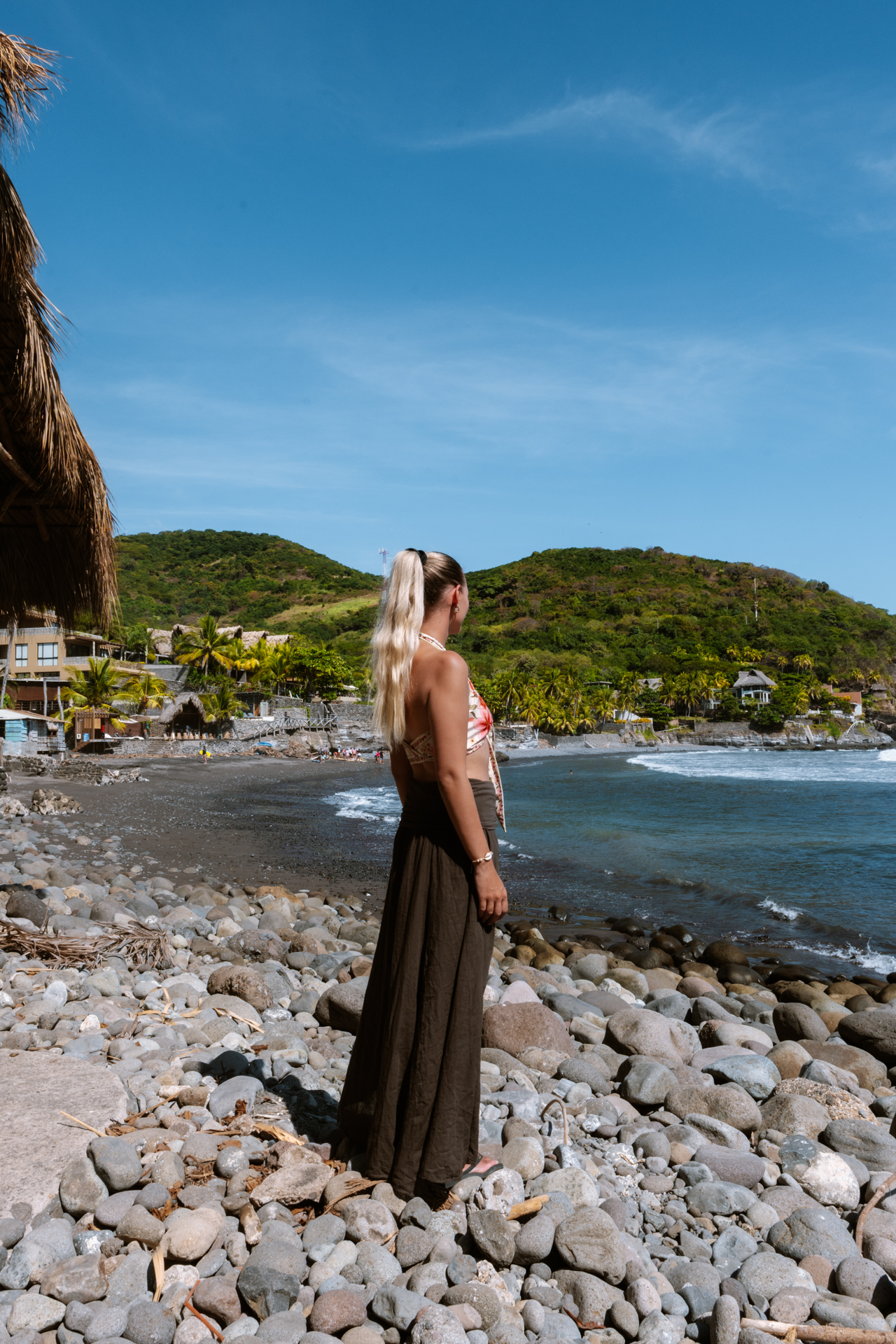 Traveler overlooking El Zonte beach with black sand and ocean waves