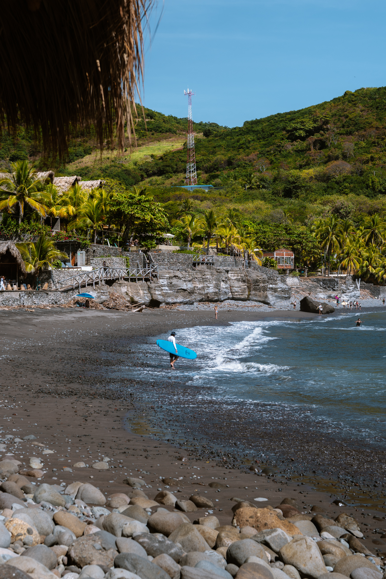 Surfer walking along El Zonte Beach, El Salvador