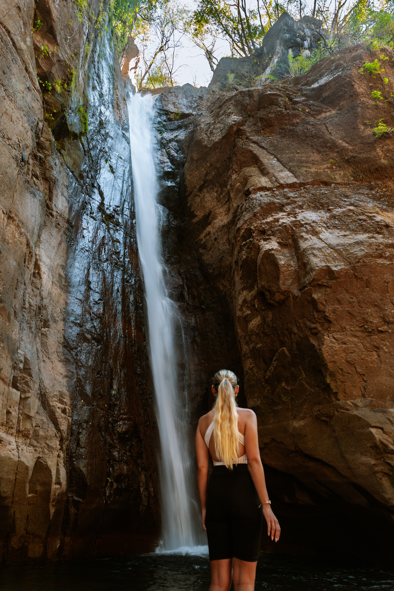Traveler admiring Tamanique Waterfalls cascading through rocky canyon in El Salvador