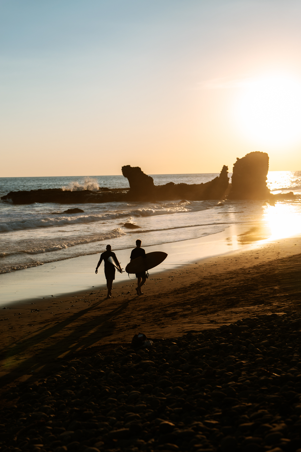 Surfers walking at sunset in El Tunco, El Salvador