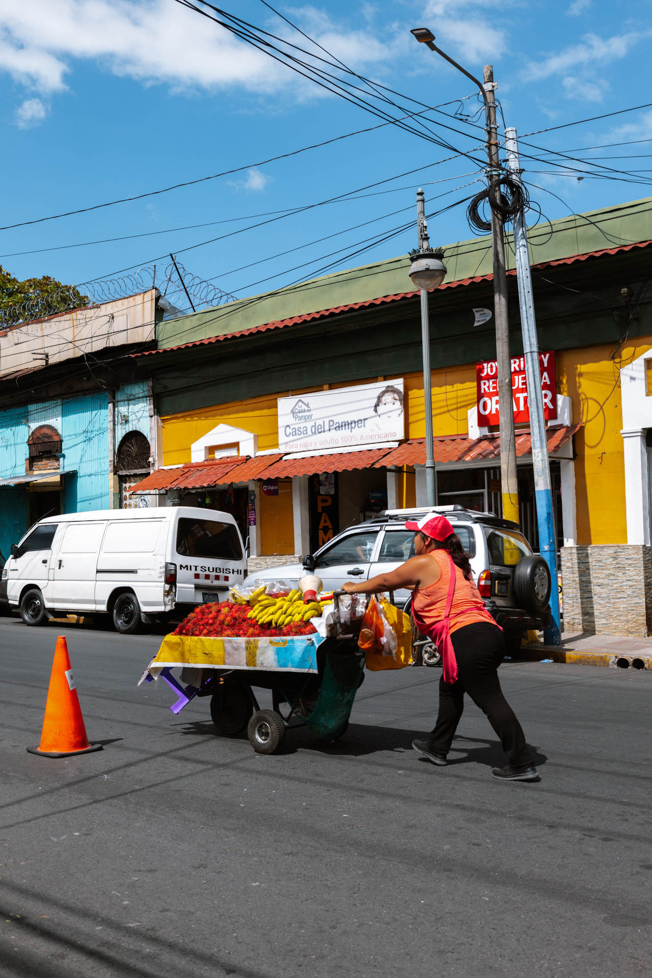 Street vendor pushing fruit cart in colorful neighborhood, El Salvador
