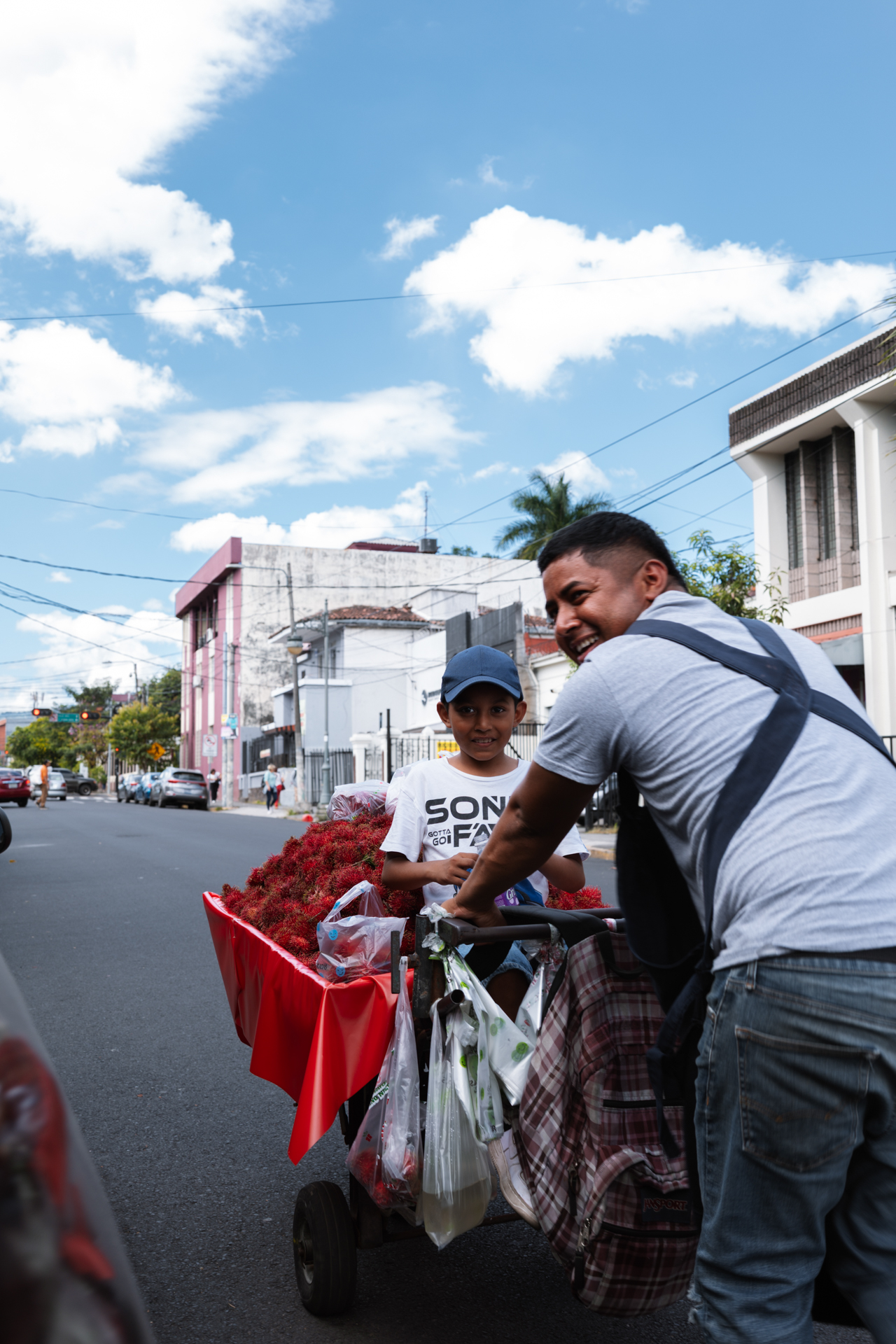 Smiling street vendors selling fruit on city street, El Salvador