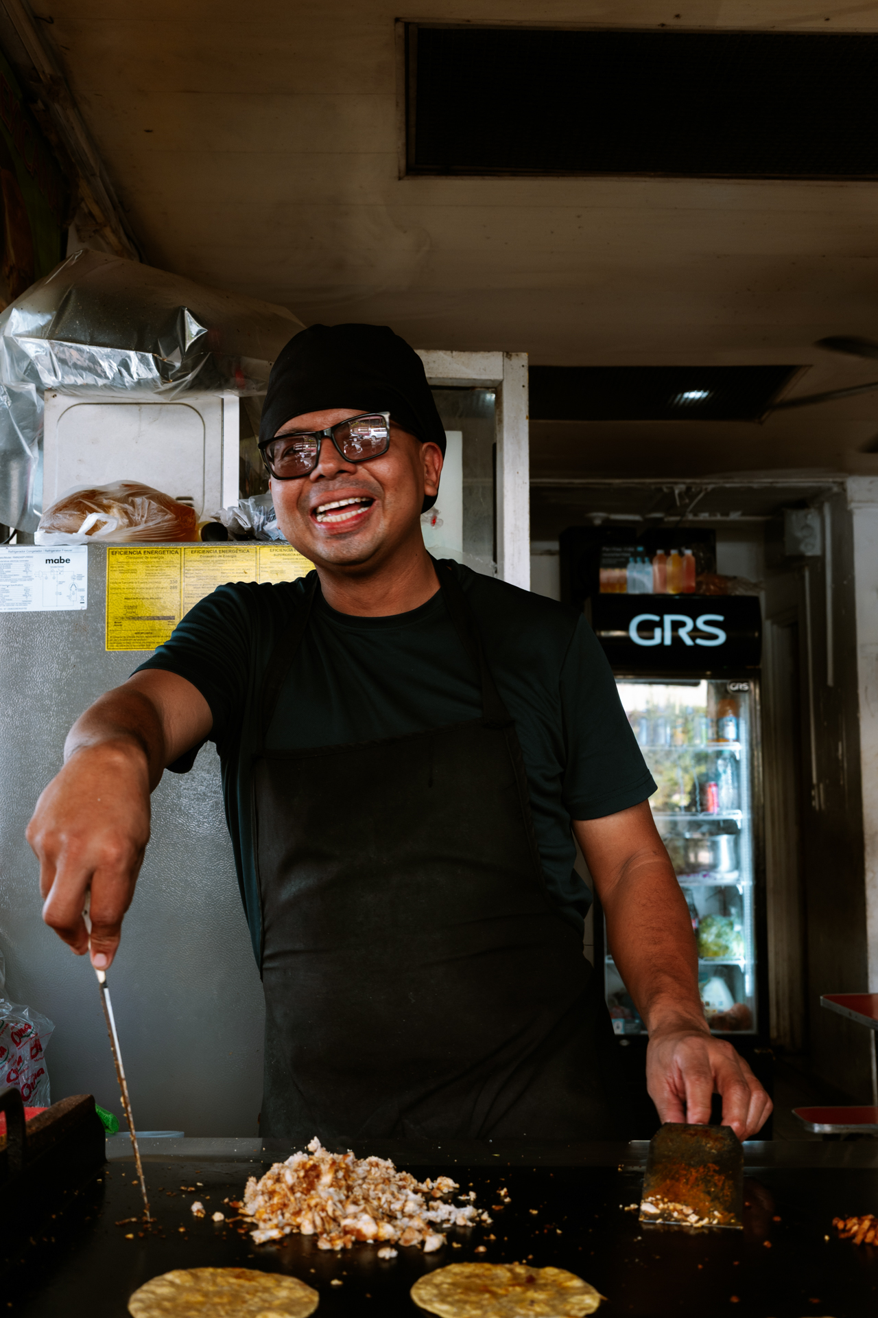 Smiling street food vendor preparing tortillas in San Salvador, El Salvador