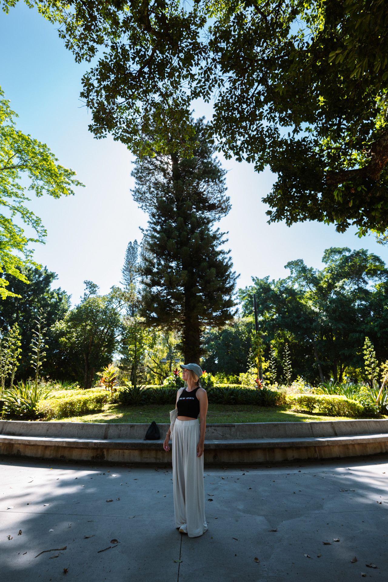Woman standing in sunny park surrounded by lush greenery in San Salvador, El Salvador