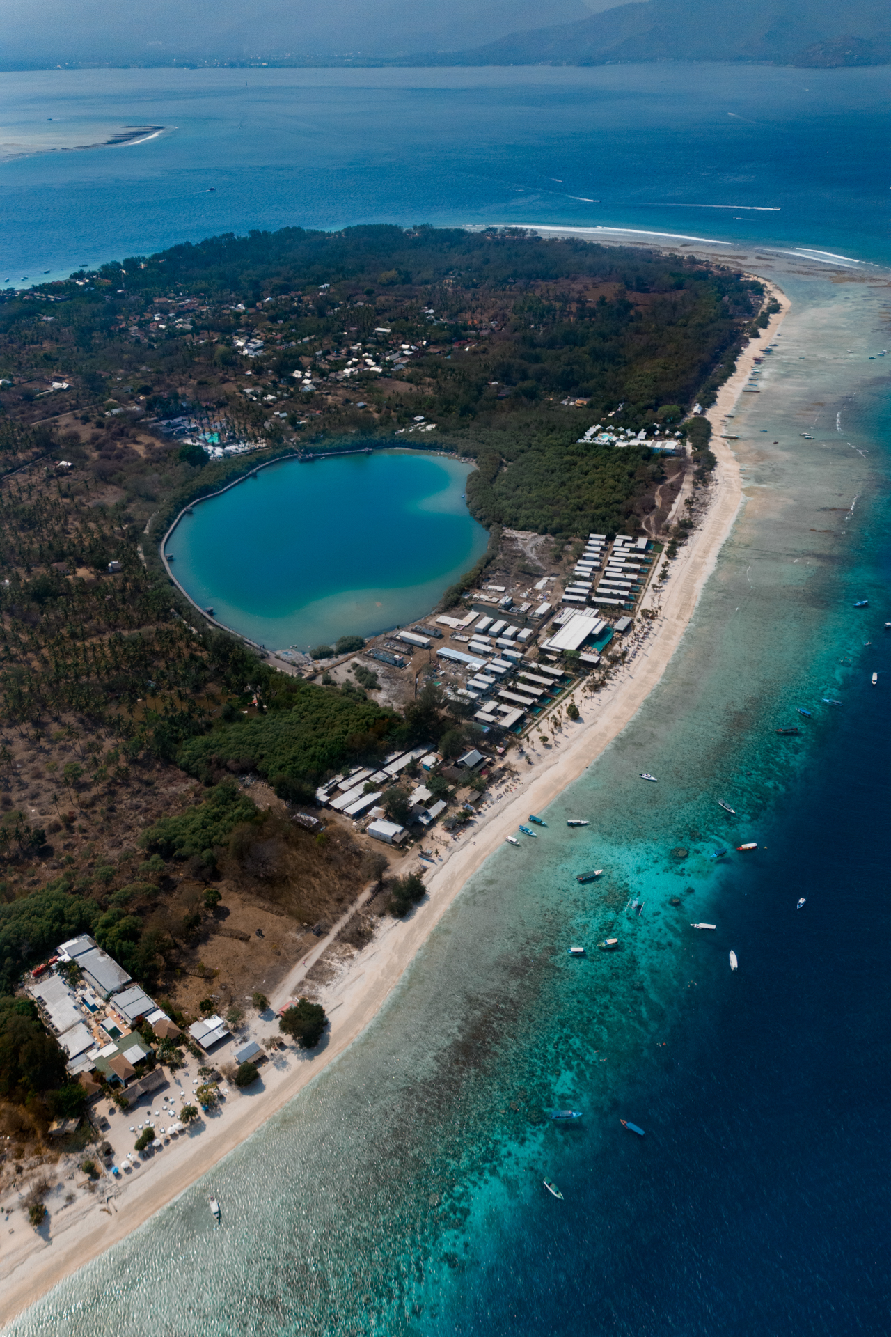 Aerial view of Gili Meno island with turquoise lagoon, white sand beaches, and surrounding coral reef, Indonesia.
