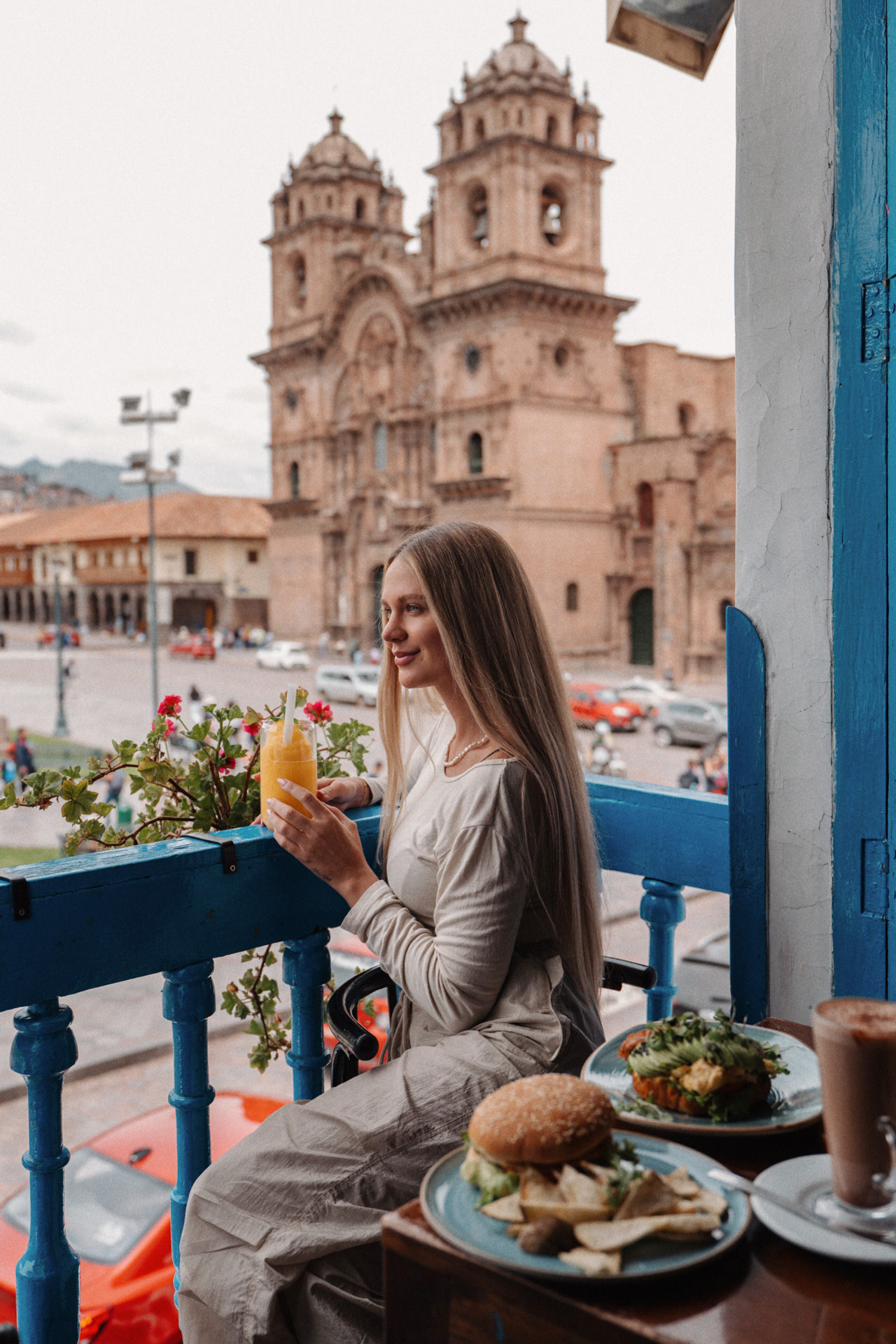 Traveler enjoying breakfast on a balcony with views of Cusco Cathedral, Peru