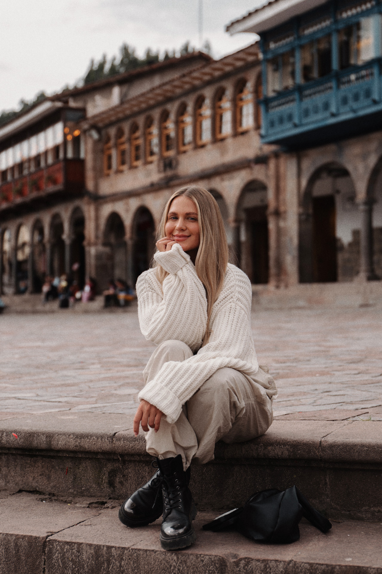 Traveler sitting in Cusco’s Plaza de Armas with historic arcades in the background