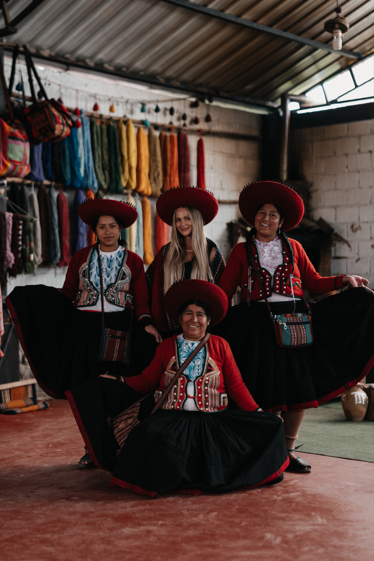 Women in traditional clothing posing in a textile workshop in Chinchero, Peru