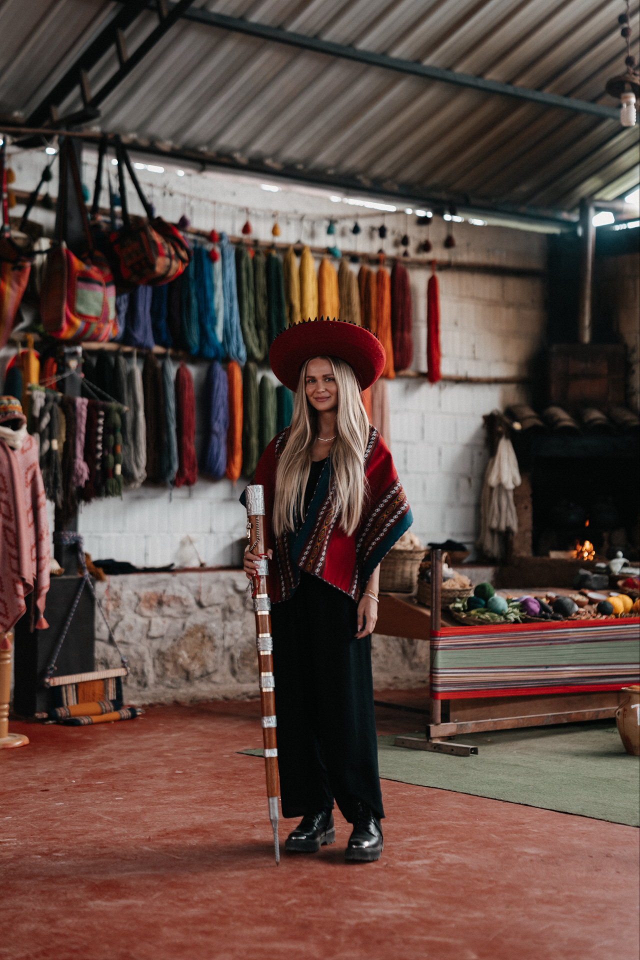 Traveler wearing traditional Peruvian poncho and hat inside a local weaving workshop in Chinchero