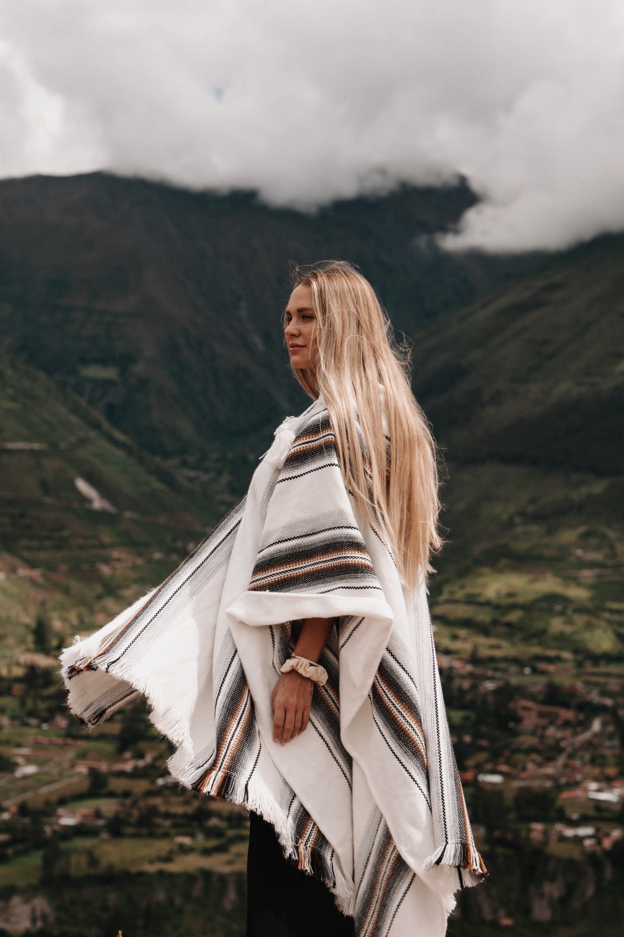 Woman wearing a traditional poncho overlooking the Sacred Valley mountains in Peru