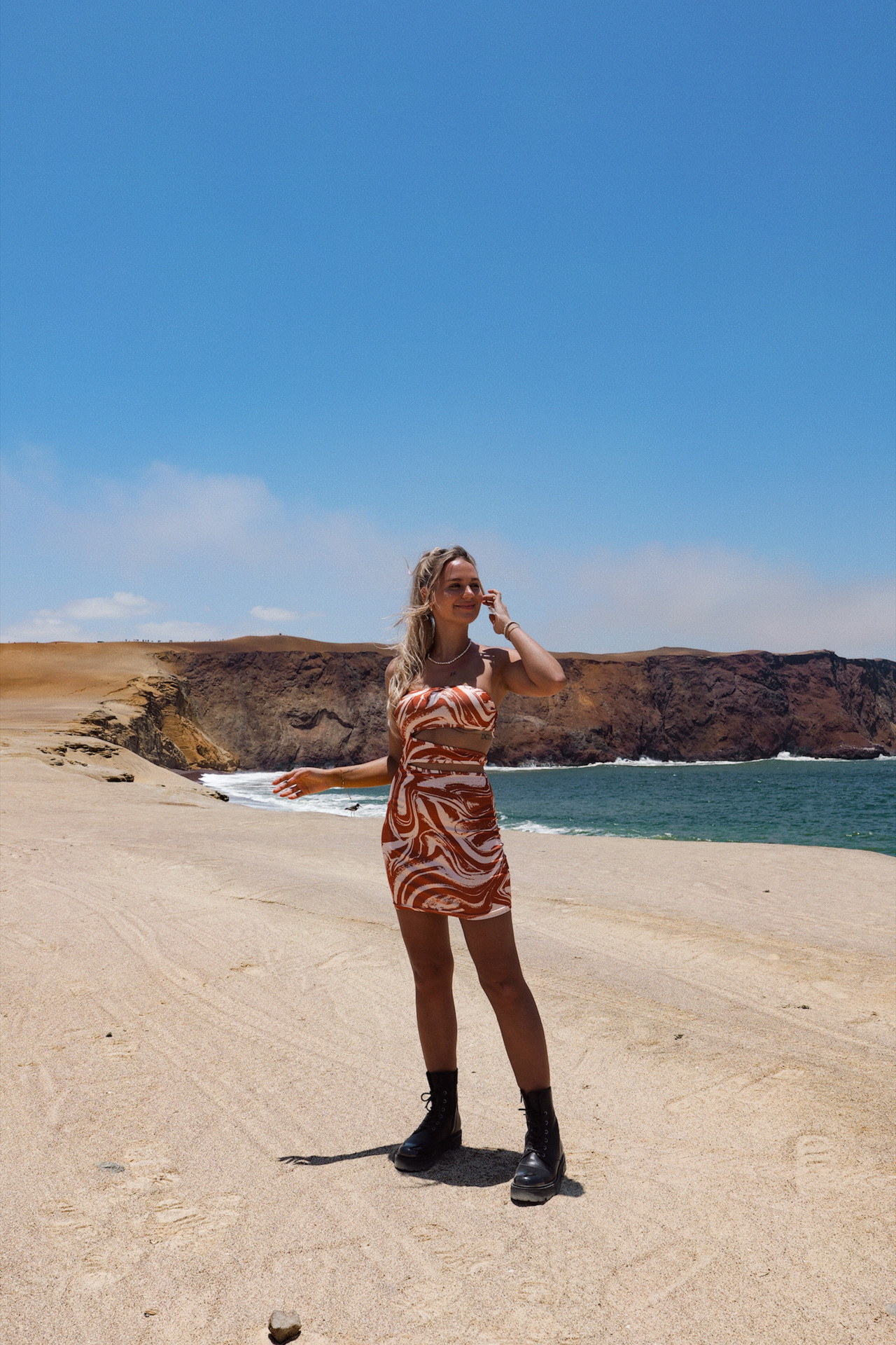 Traveler standing on a rocky beach in Paracas with desert cliffs and ocean views