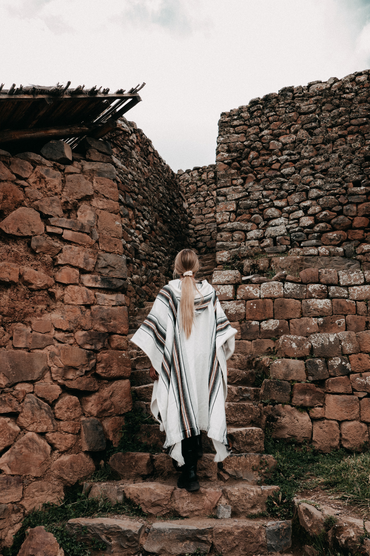 Woman walking up ancient stone steps at the Pisac ruins in the Sacred Valley, Peru