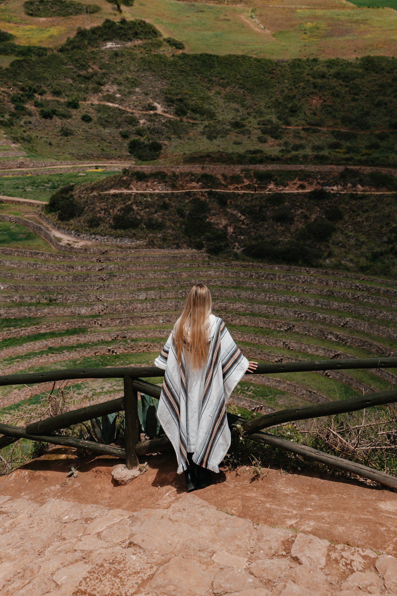 Traveler standing above the circular terraces of Moray archaeological site in Peru