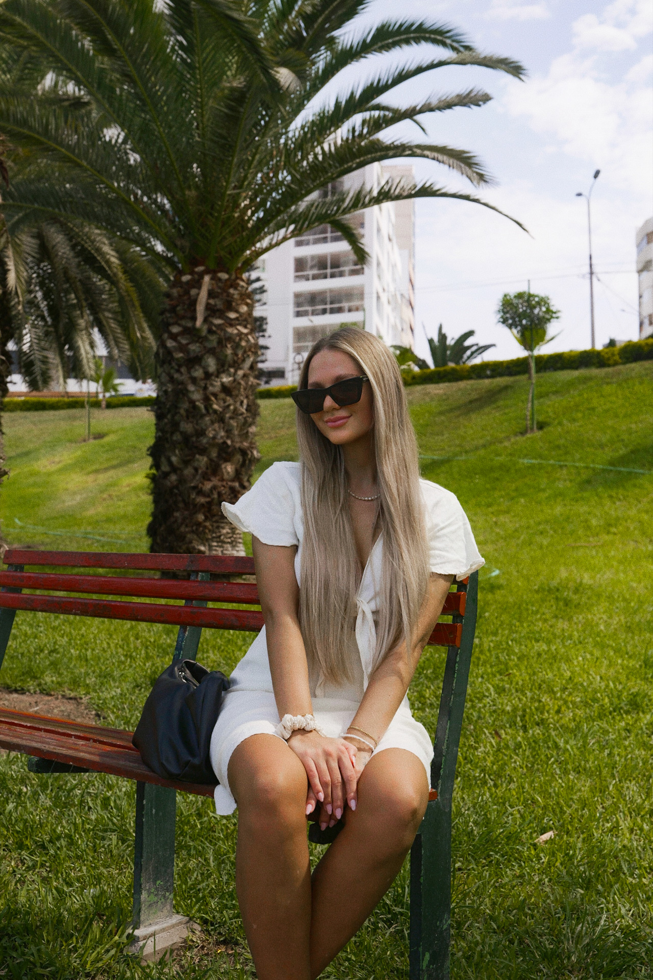 Traveler sitting on a park bench in Lima surrounded by palm trees and green lawns