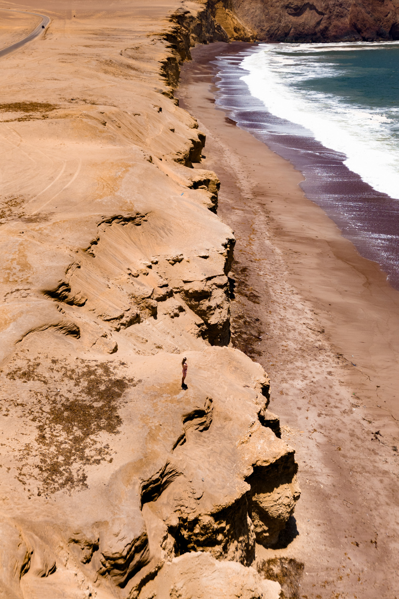 Aerial view of desert cliffs meeting the Pacific Ocean in Paracas, Peru at Playa Roja