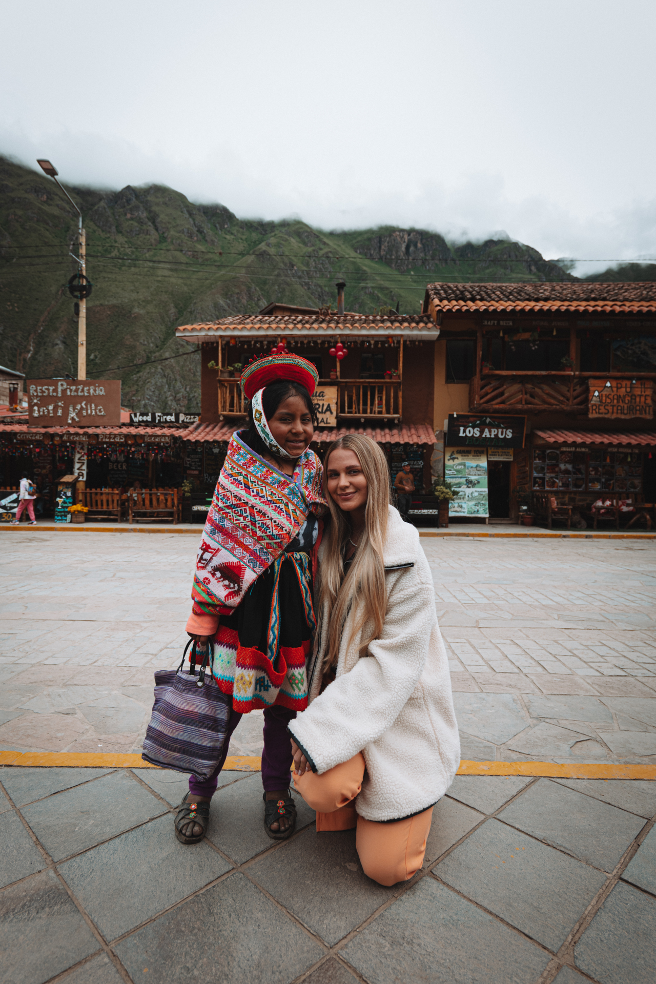 Traveler posing with local woman in traditional dress in Ollantaytambo village, Peru