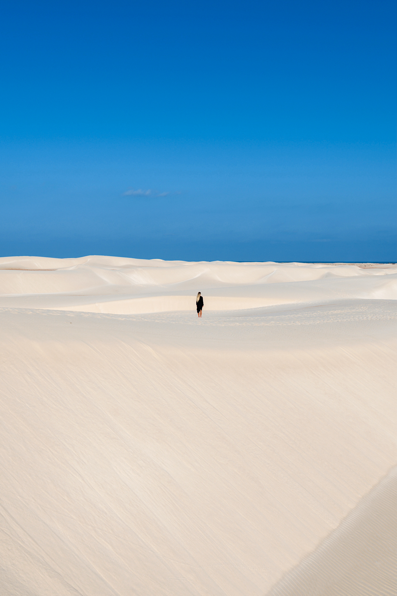 A person walking across the white sand dunes of Zahek Dunes on Socotra Island.