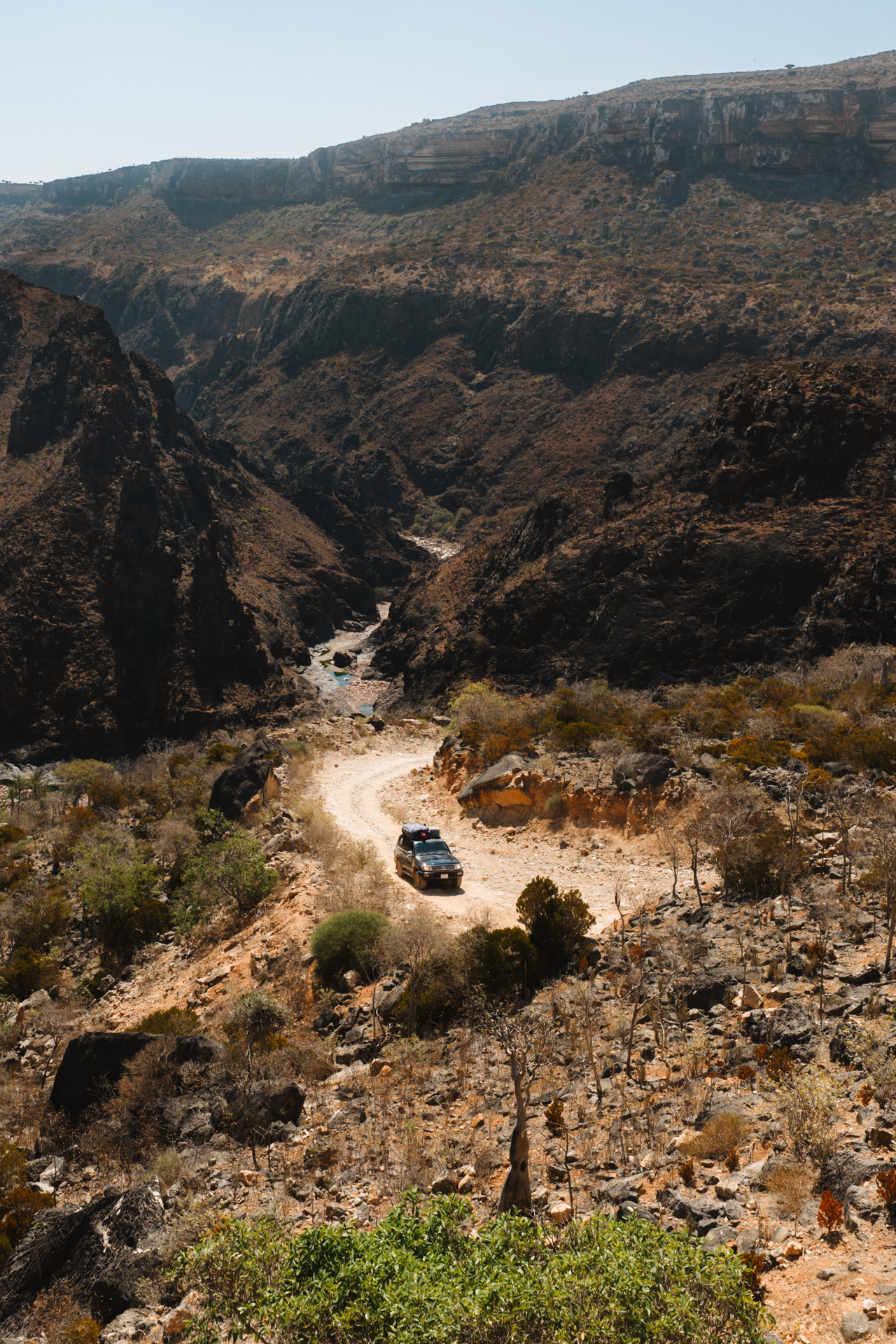 Off-road vehicle winding through rugged mountain terrain on Socotra Island.