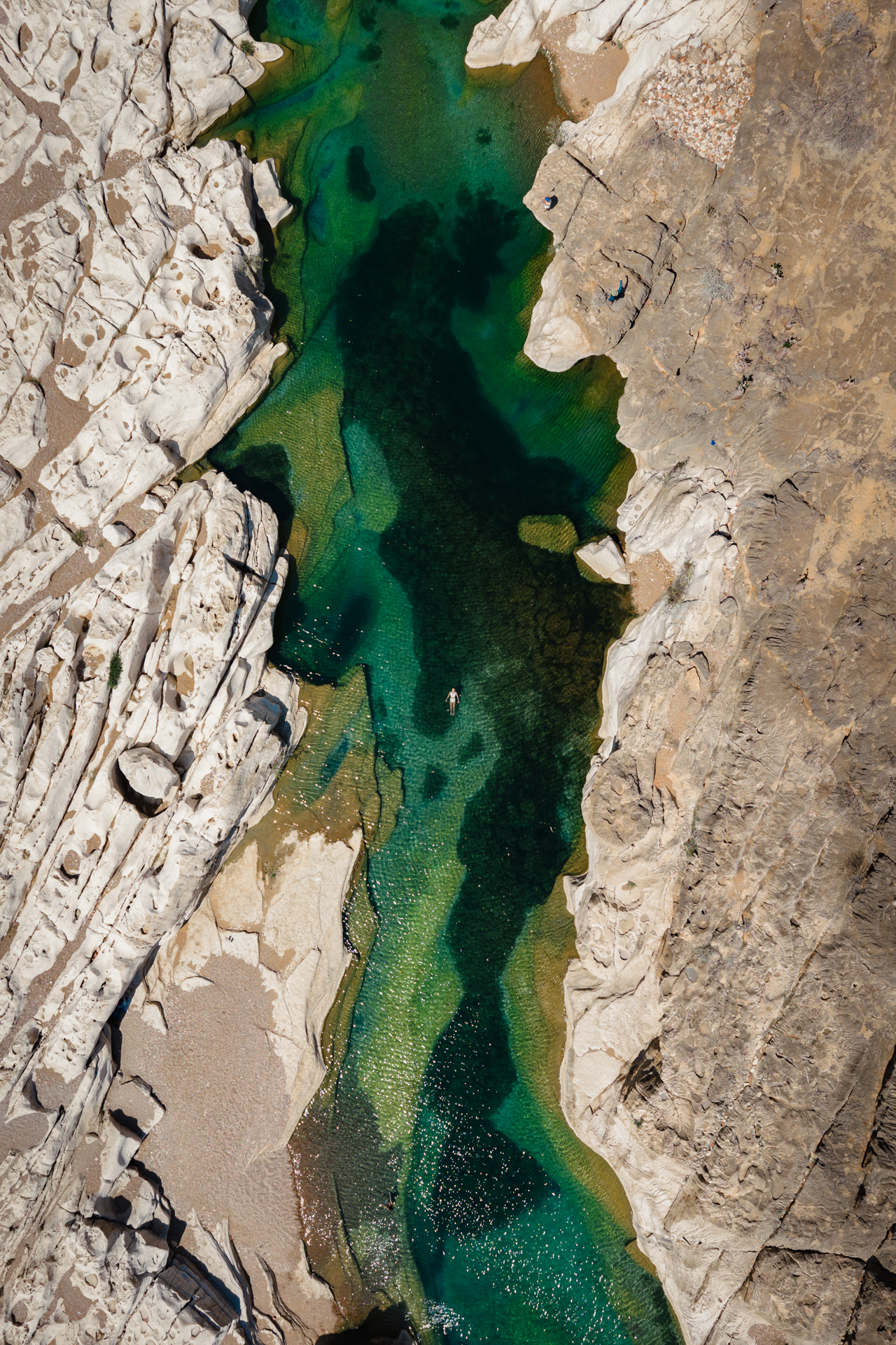 Aerial view of a swimmer in clear emerald waters of Wadi Kalissan.