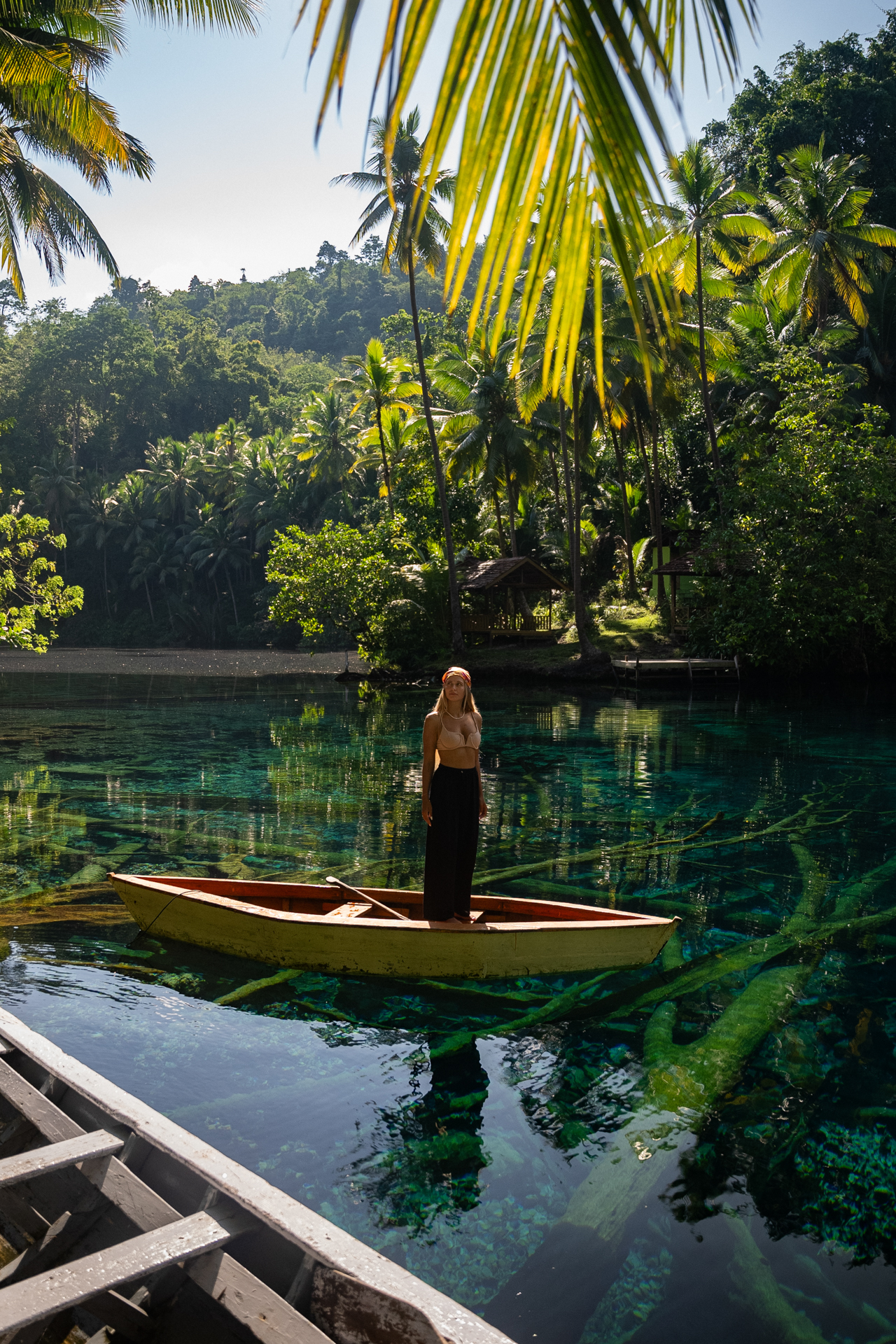 Woman standing in wooden boat at Paisu Pok Lake on crystal clear lagoon, Banggai Islands