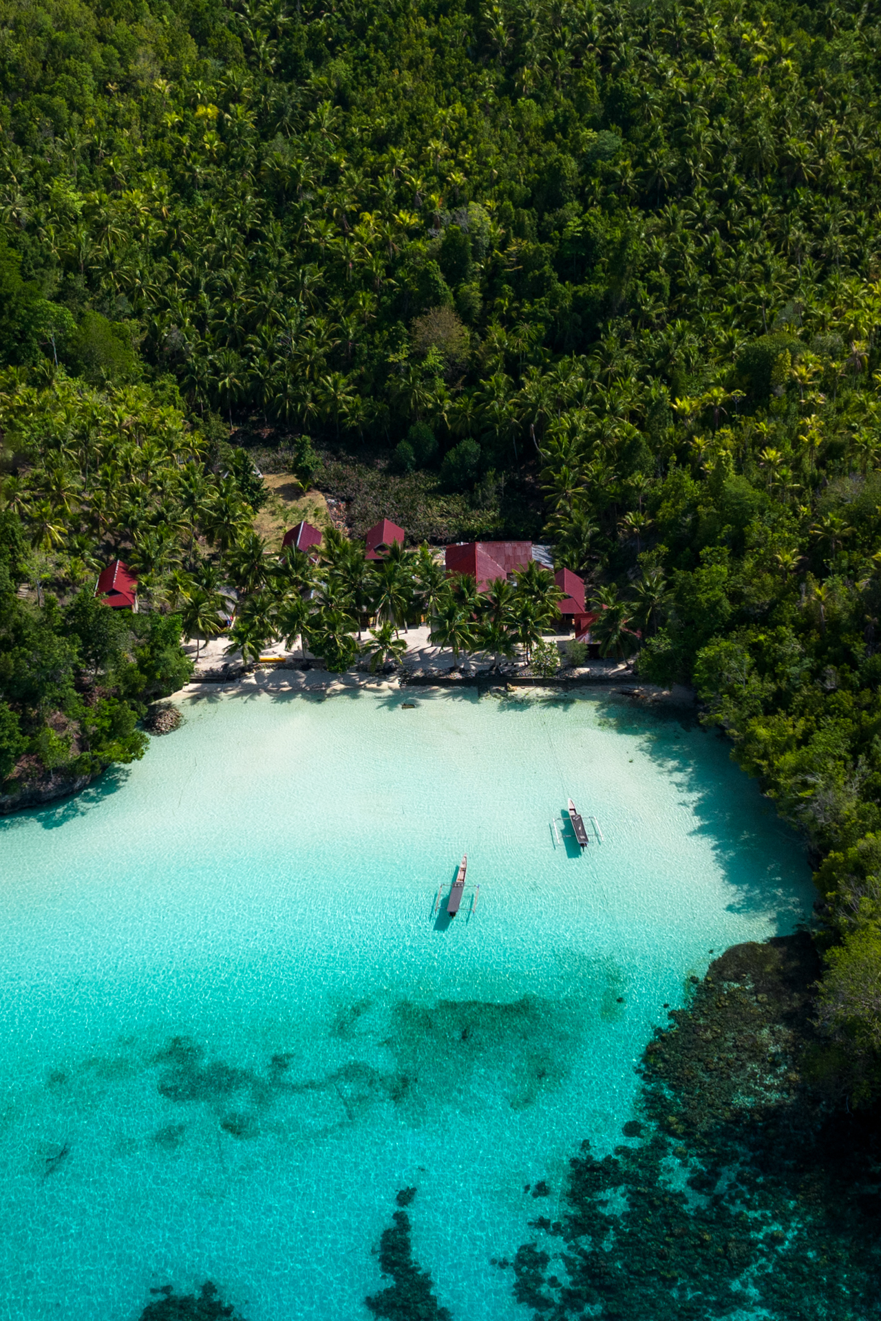 Aerial view of Togian Islands lagoon with boats and tropical jungle