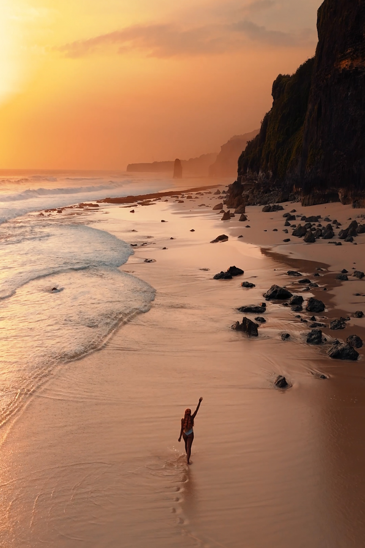 Woman walking on Mbawana Beach at sunset, Sumba Island