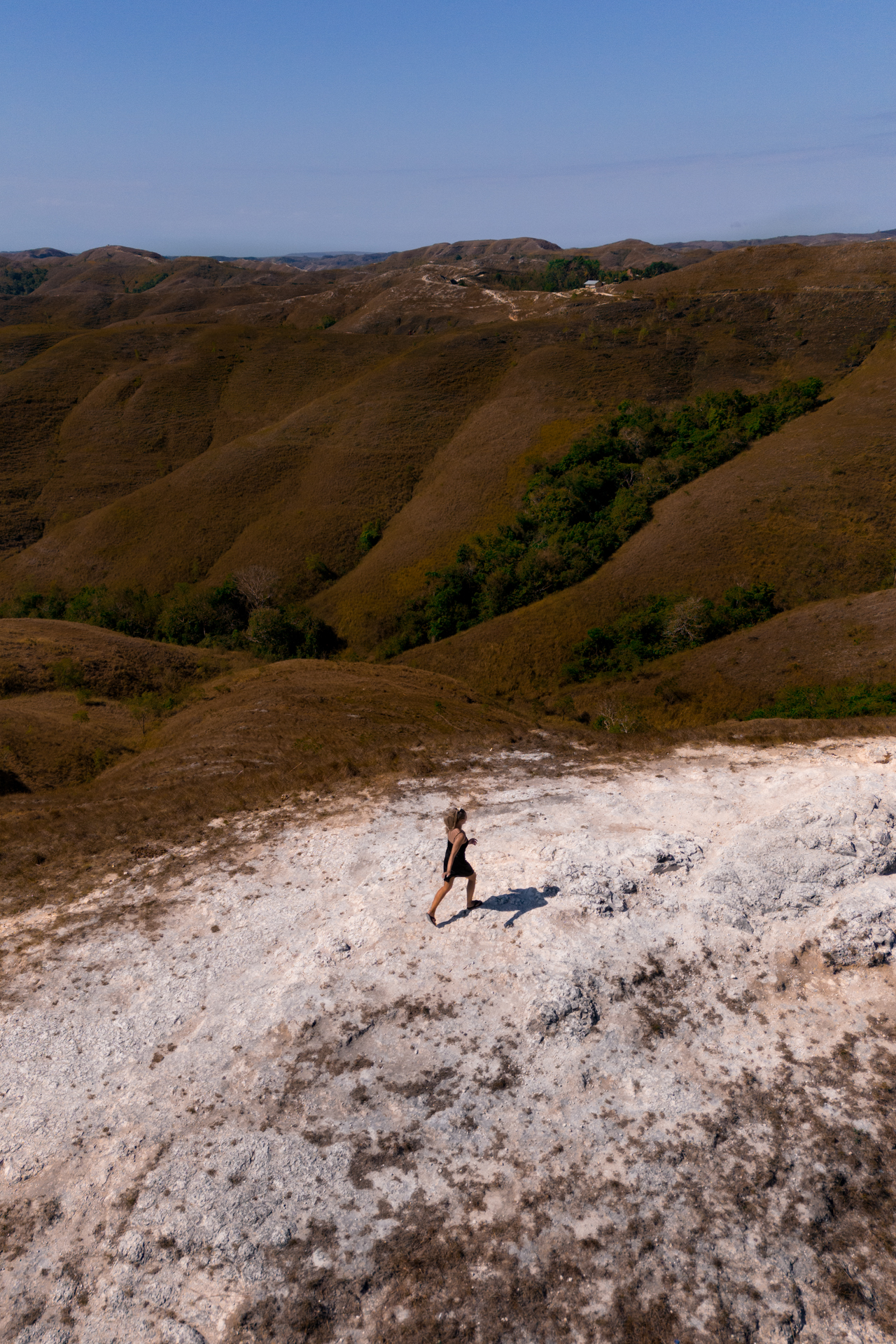 Woman walking on Wairinding Hill with rolling landscape, Sumba Island