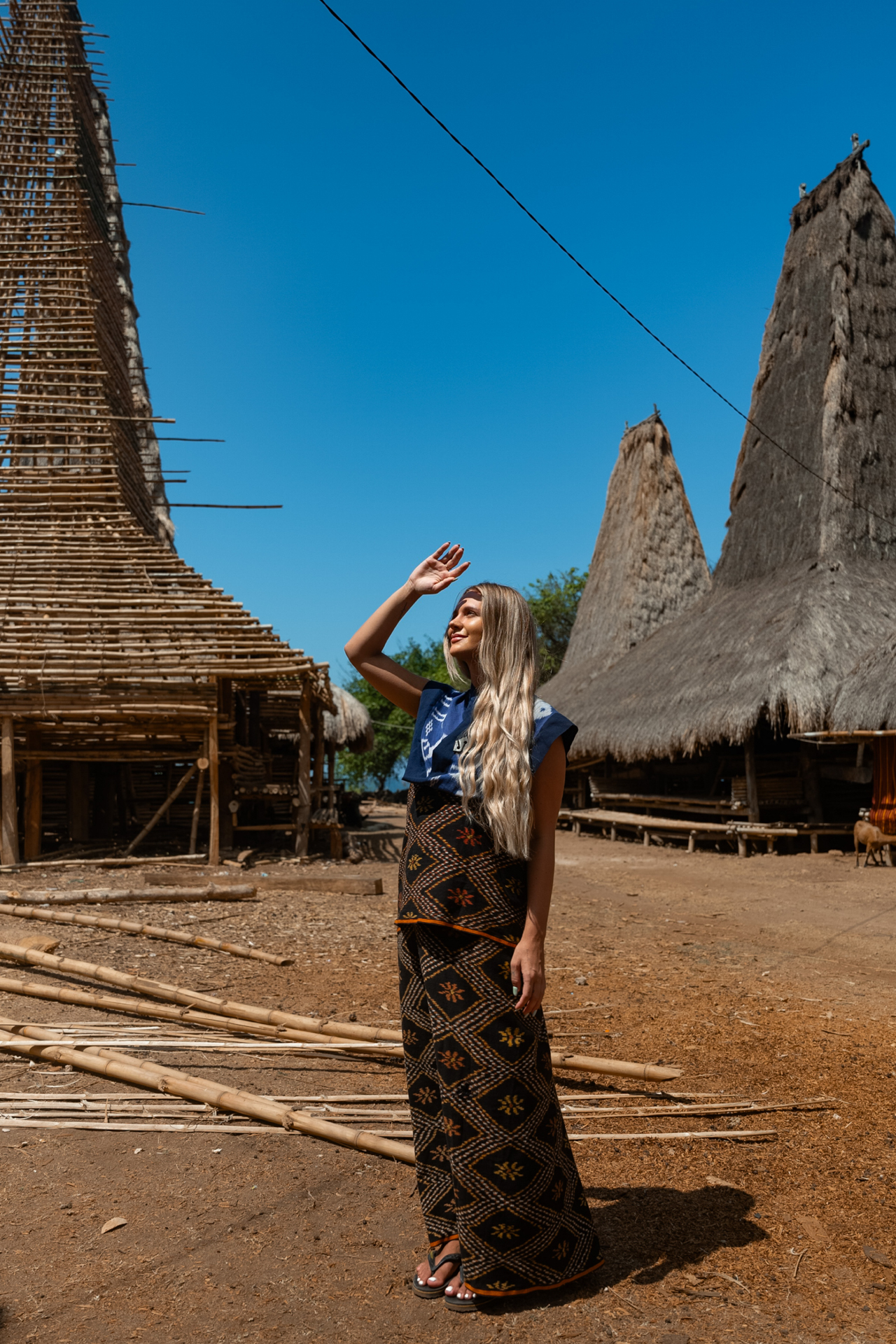 Woman in traditional dress in Sumba village with thatched houses