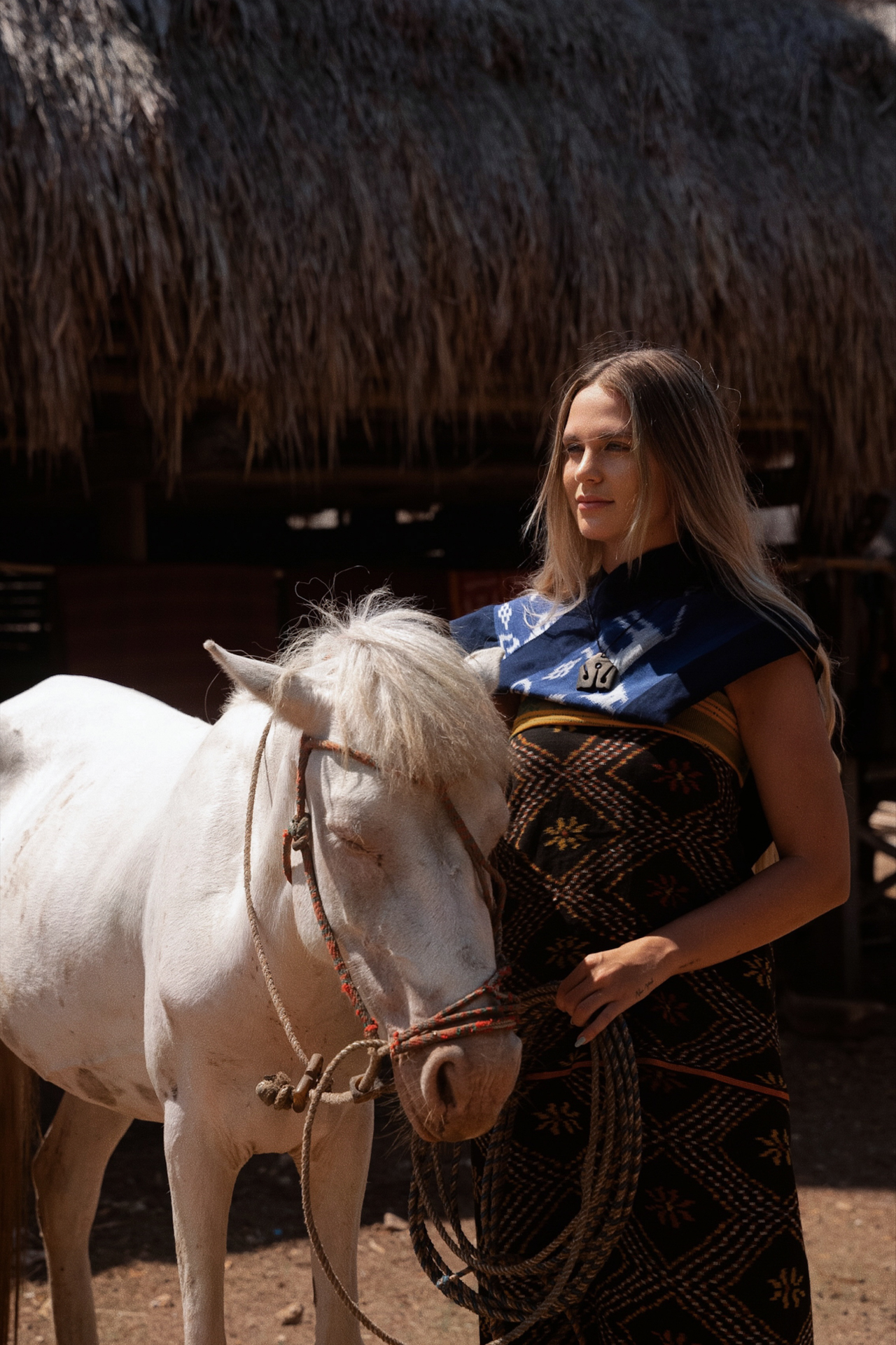 Woman with white horse in traditional village, Sumba Island