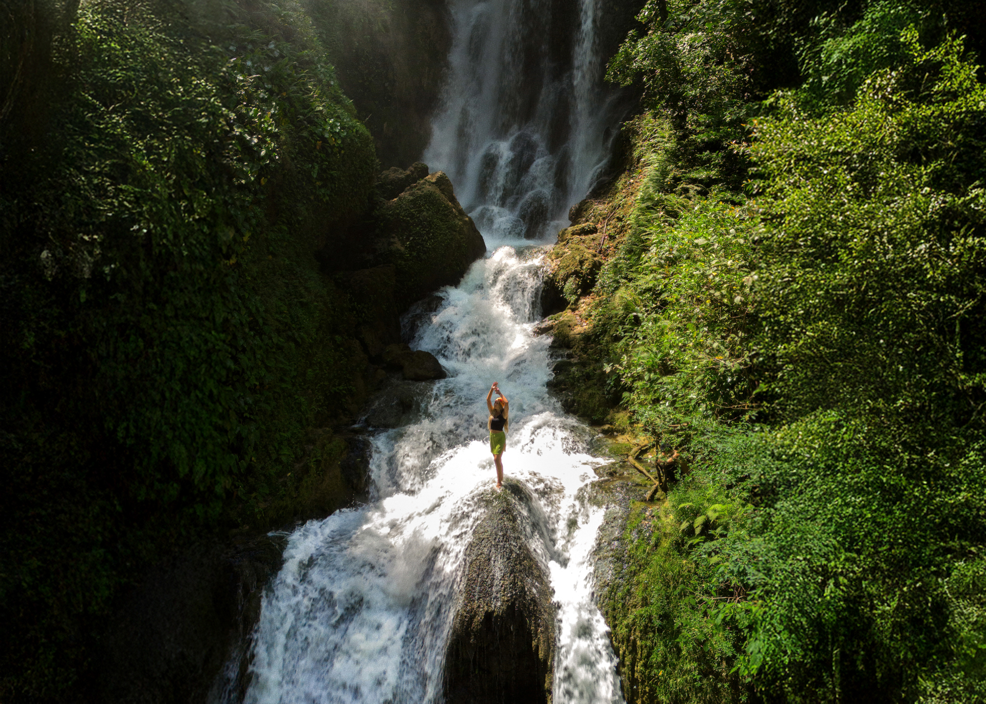 Woman standing on a rock at Lokomboro waterfall in Sumba, Indonesia
