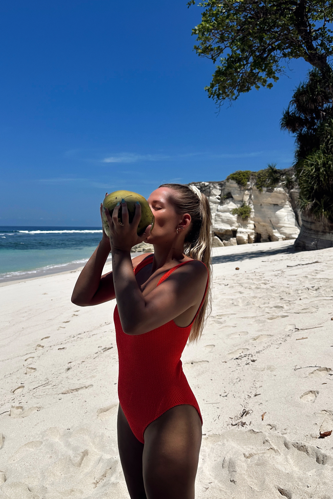 Woman drinking coconut at Watu Bela Beach, Sumba Island