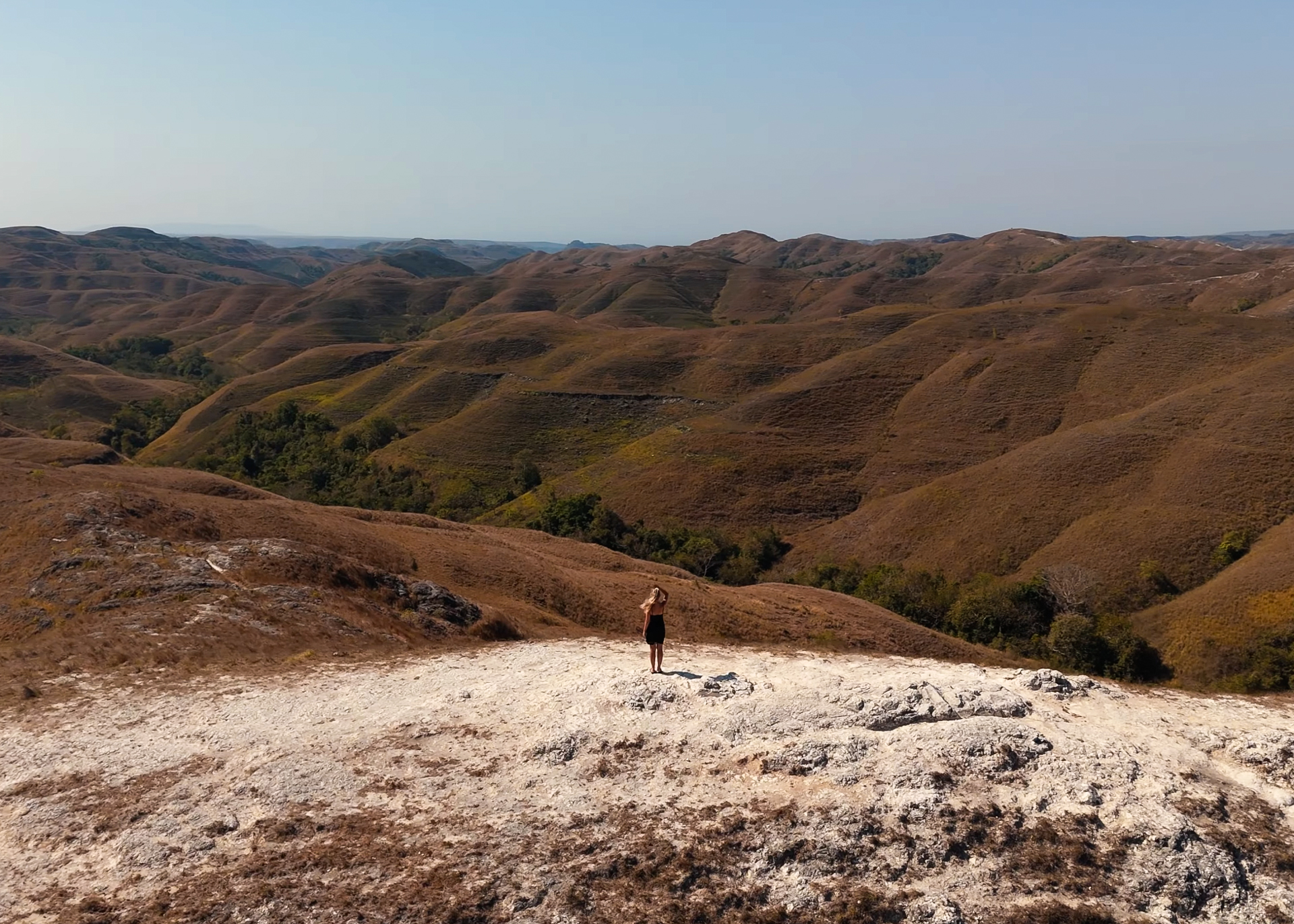 Woman standing on Wairinding Hill with rolling landscape, Sumba Island