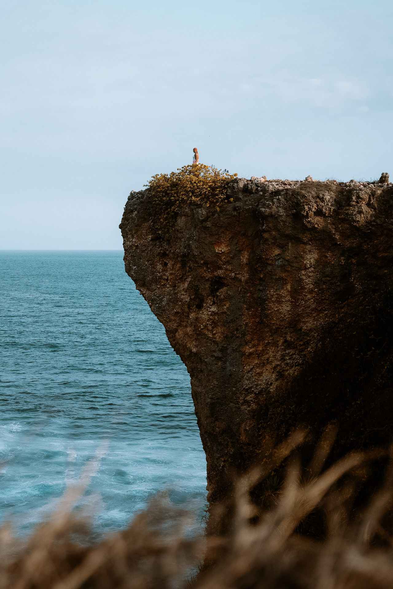 Woman standing on cliff above ocean, Sumba Island