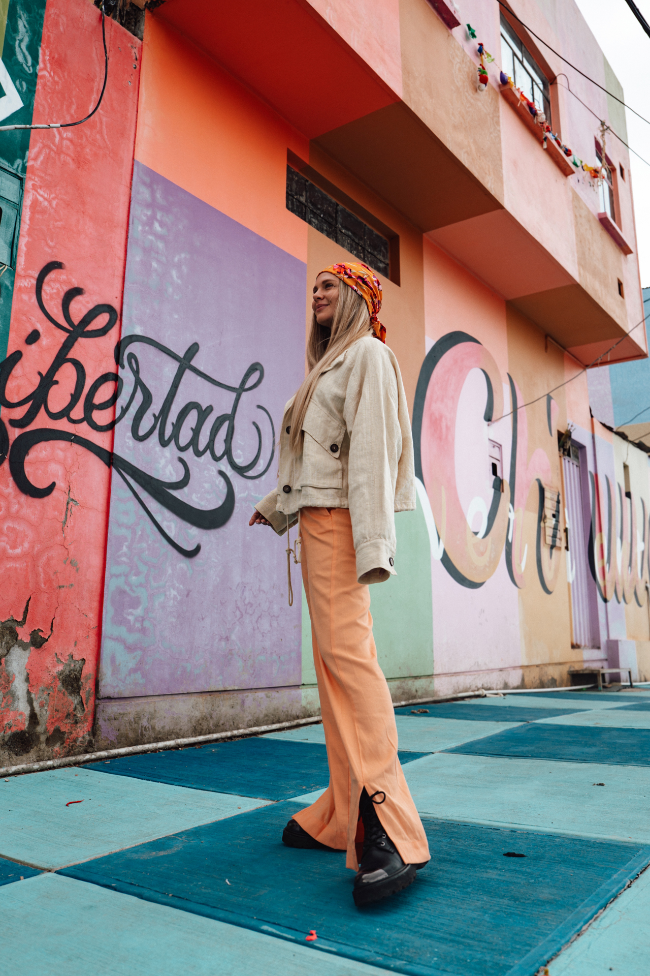Woman standing in front of colorful murals in the vibrant Chualluma neighborhood of La Paz, Bolivia.