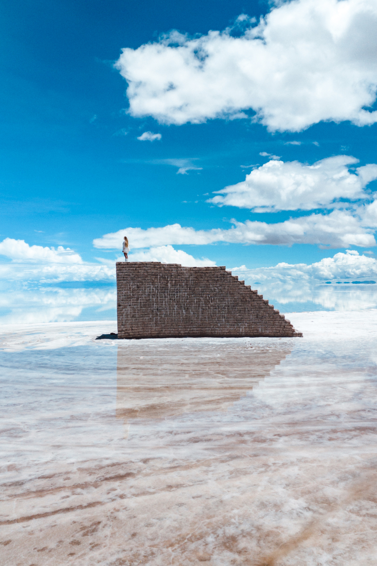Standing atop the salt stairs of Salar de Uyuni, surrounded by endless reflections and blue skies.