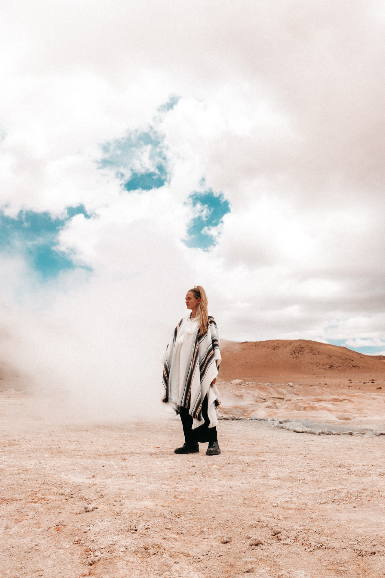 Woman standing beside steam vents at Sol de Mañana geysers in Eduardo Avaroa National Reserve, Bolivia.
